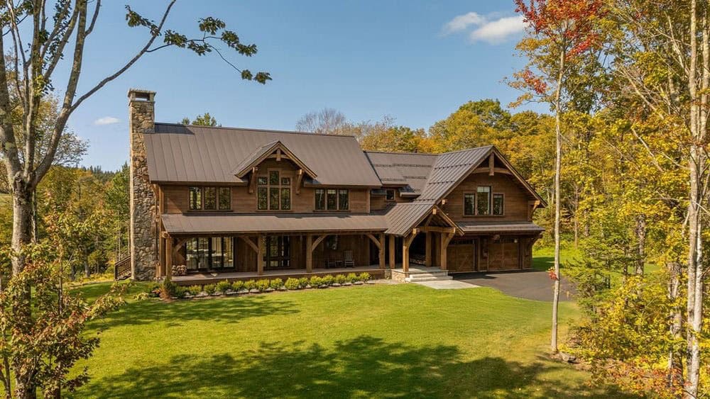Aerial exterior view of timber frame home with metal roof in autumn landscape