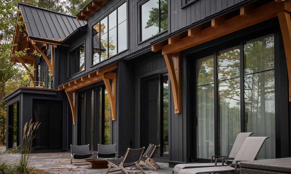 Close-up of cottage rear facade with timber bracket details, large sliding glass doors, and patio lounge chairs