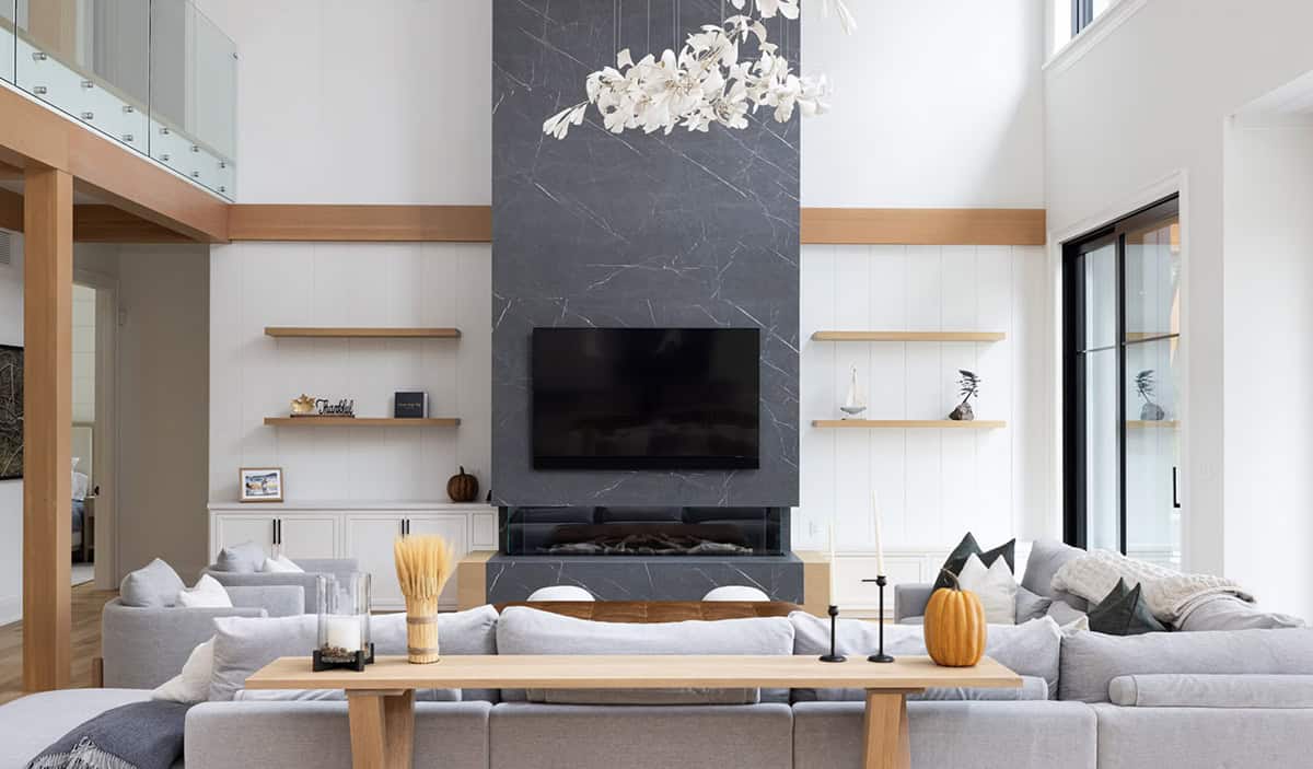 Living room focused on floor-to-ceiling dark marble fireplace with built-in shelving and white floral chandelier above