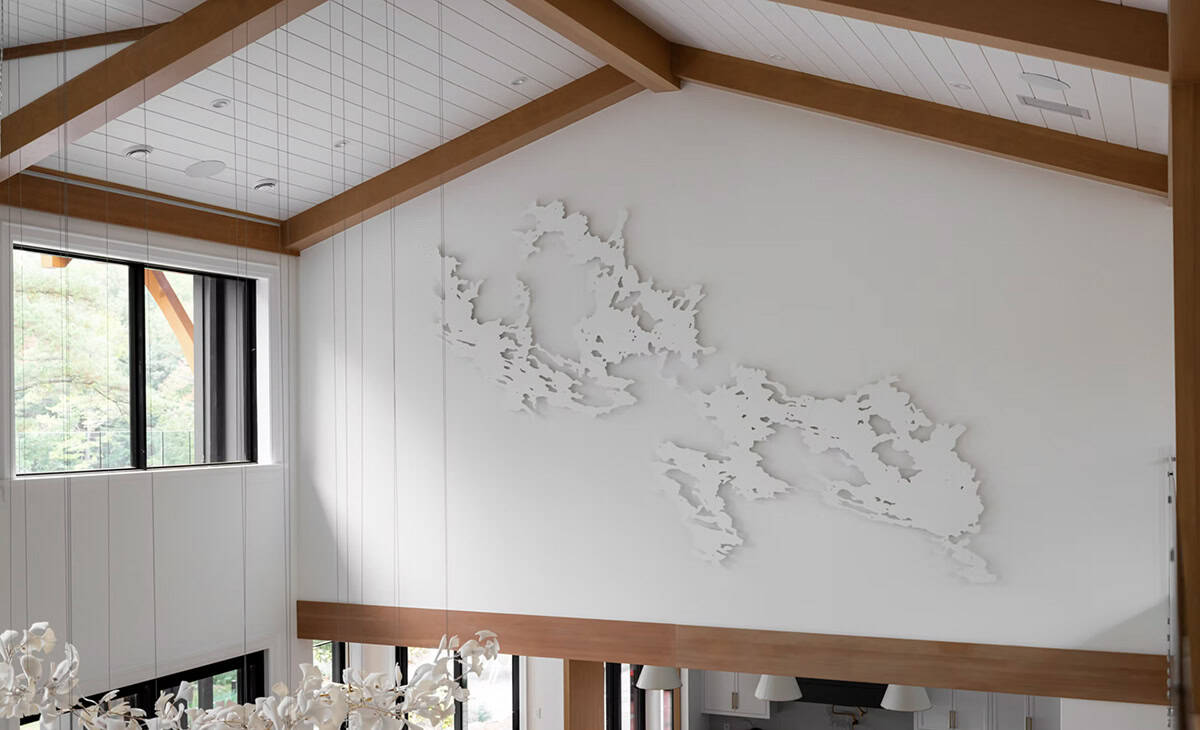 Large-scale white wall sculpture of Lake Muskoka shoreline displayed on a high gable wall with timber beams