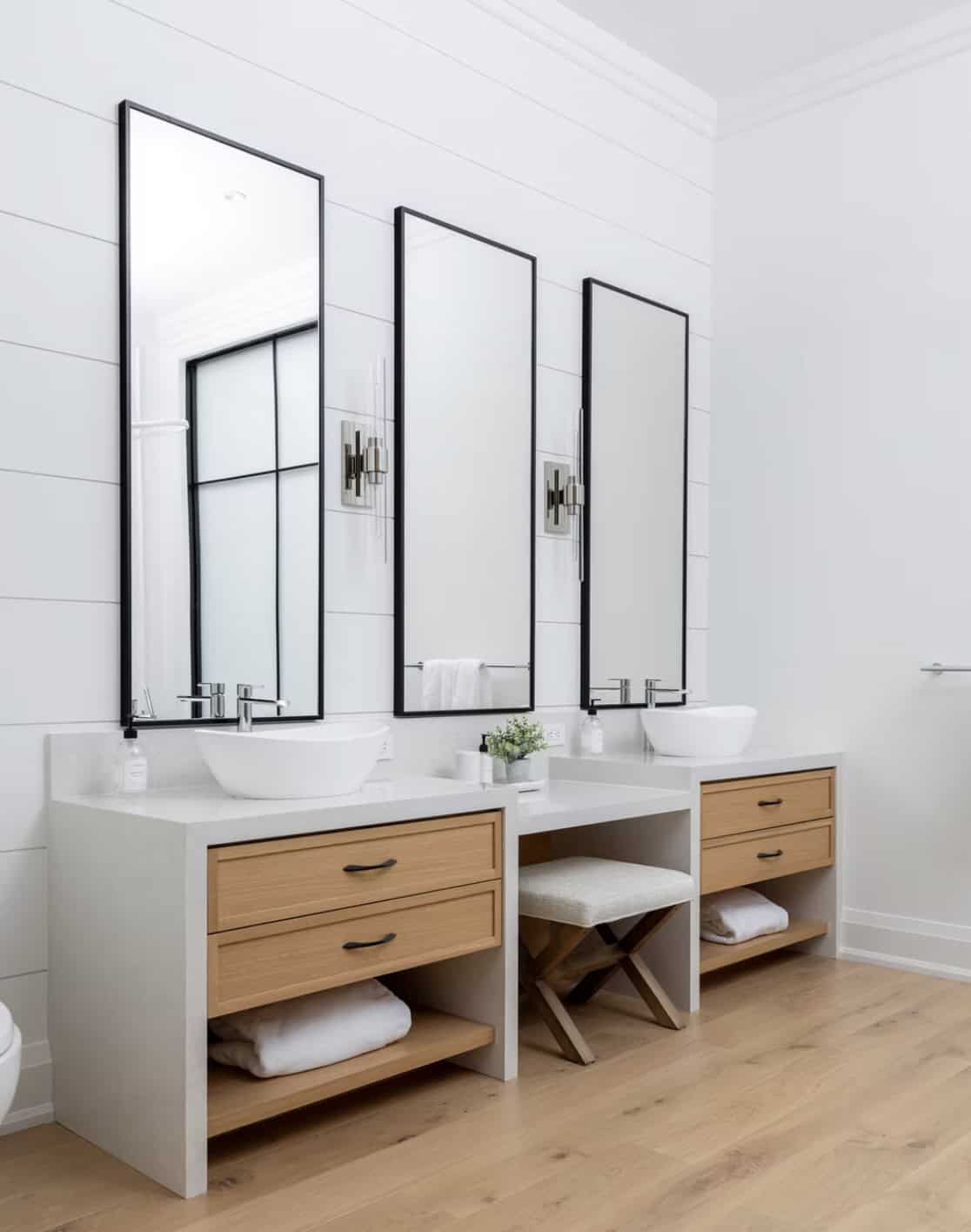 Double-sink primary bathroom vanity with vessel sinks, oak drawers, black-framed mirrors, and shiplap accent wall