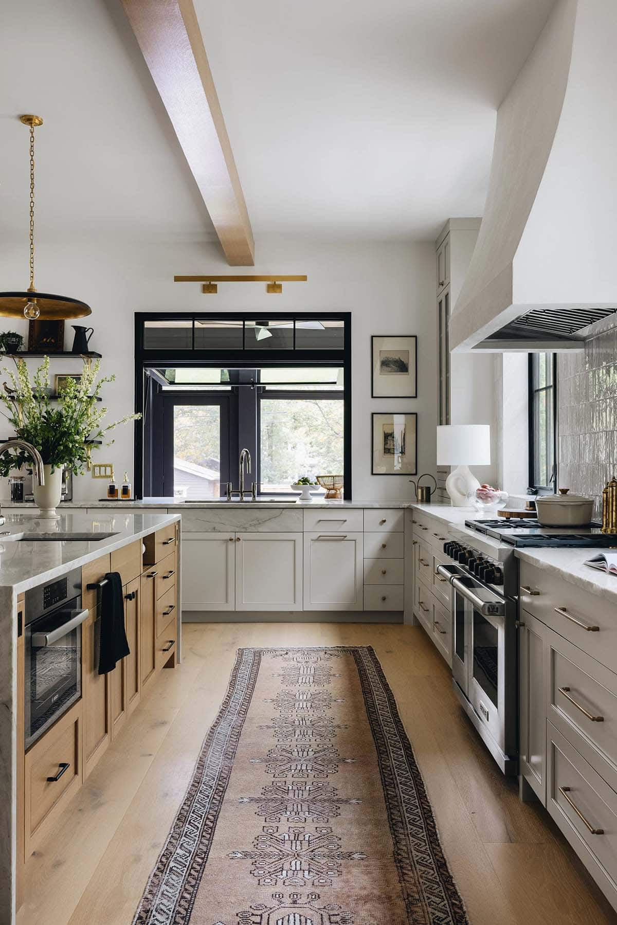 Kitchen perimeter with cream shaker cabinets, marble countertops, open black shelving, and a large black casement window above the sink