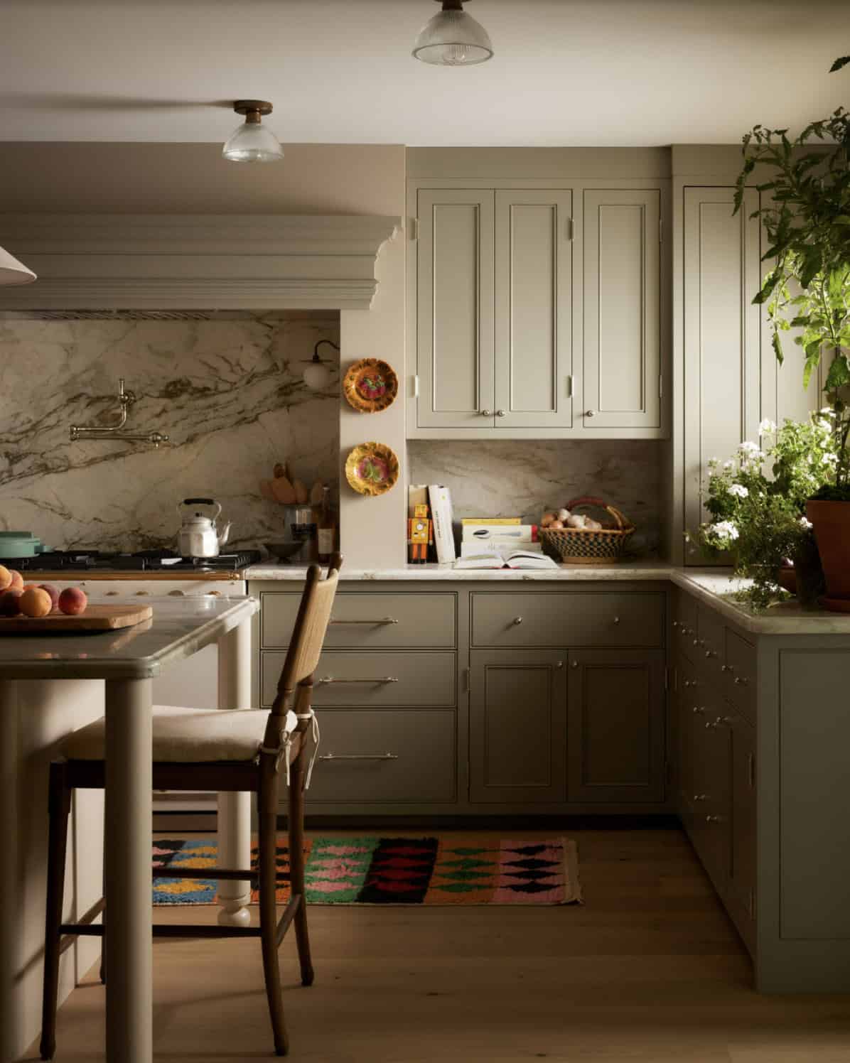 Kitchen corner with marble range wall, plates on display, and pot filler