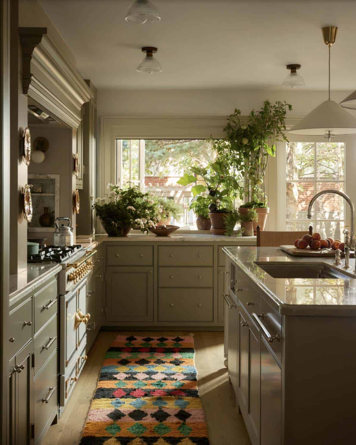 Kitchen sink area with potted herbs on windowsill and patterned runner