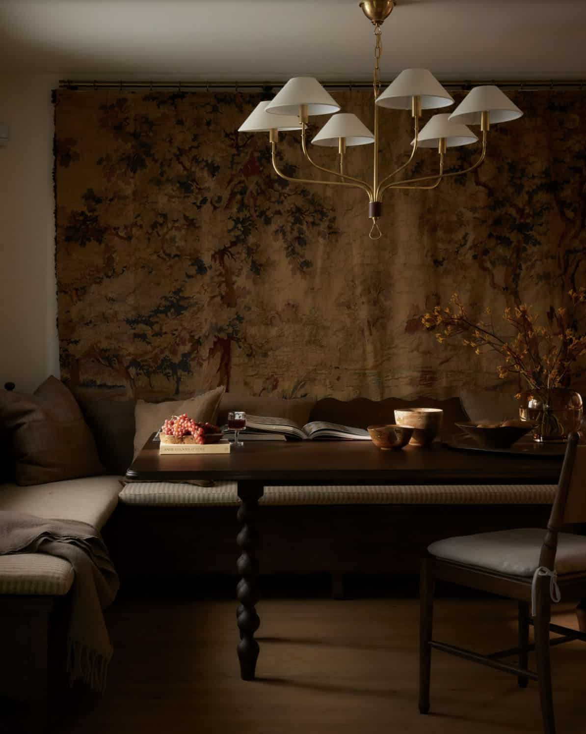 Dining nook with tapestry wall hanging and brass chandelier