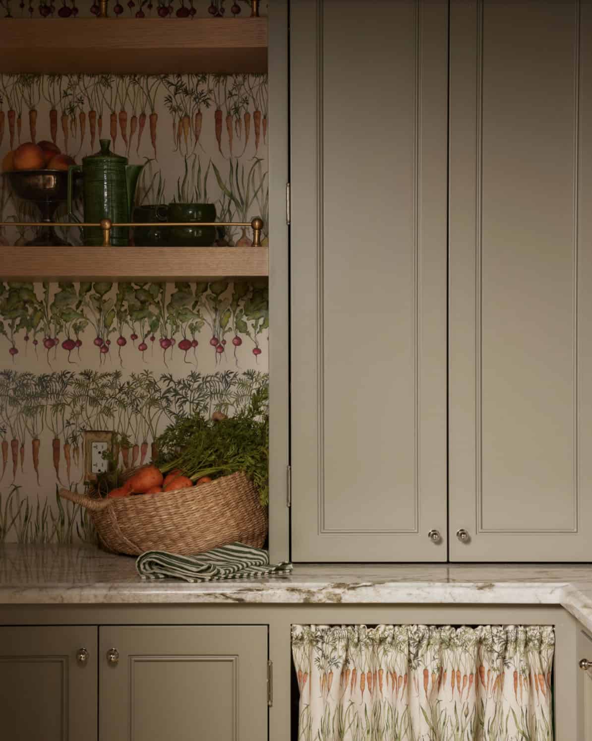 Close-up of pantry shelving with vegetable wallpaper and skirted cabinet