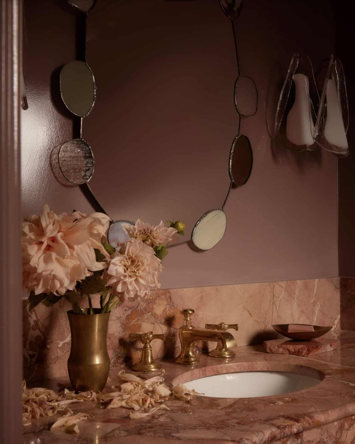 Close-up of brass faucet and stained-glass mirror in pink powder room