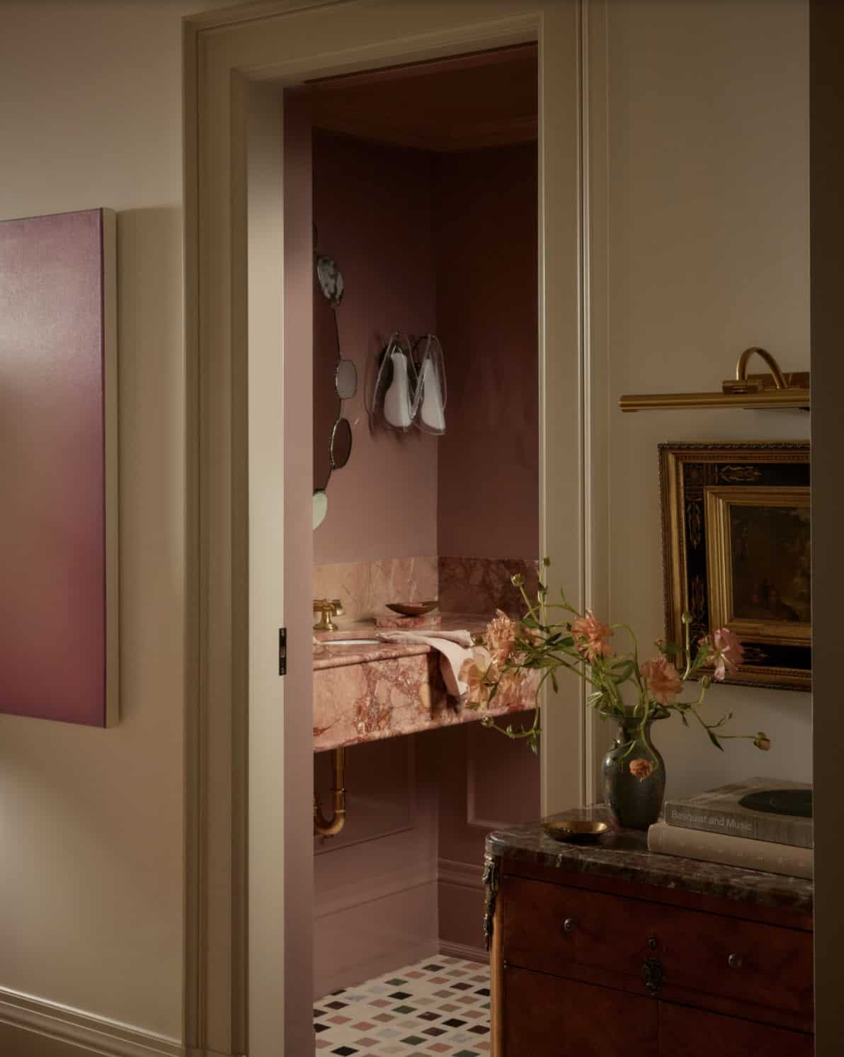 Doorway view into pink powder room from patterned-tile hallway