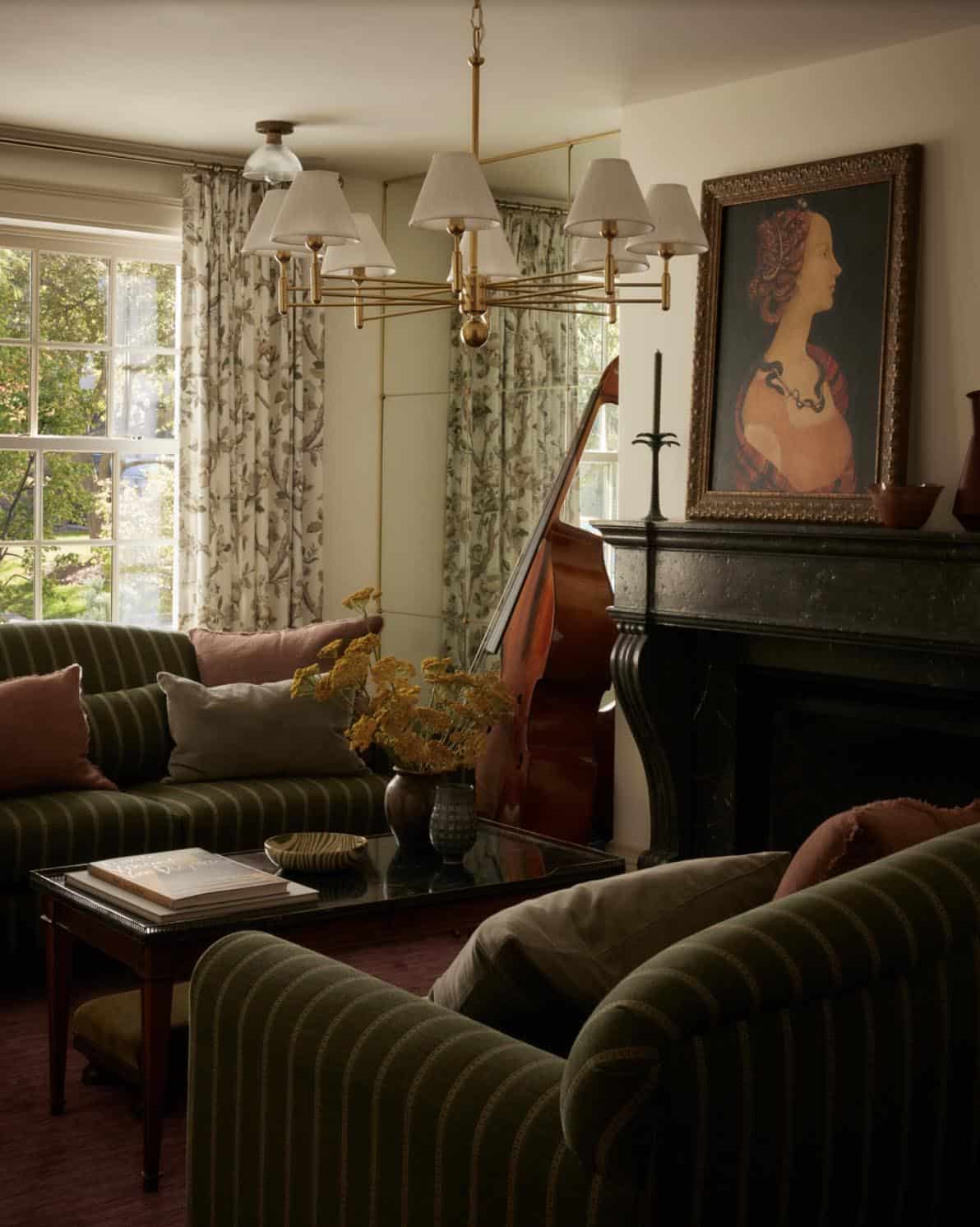 Living room with striped green sofas, dark marble mantel, and upright bass