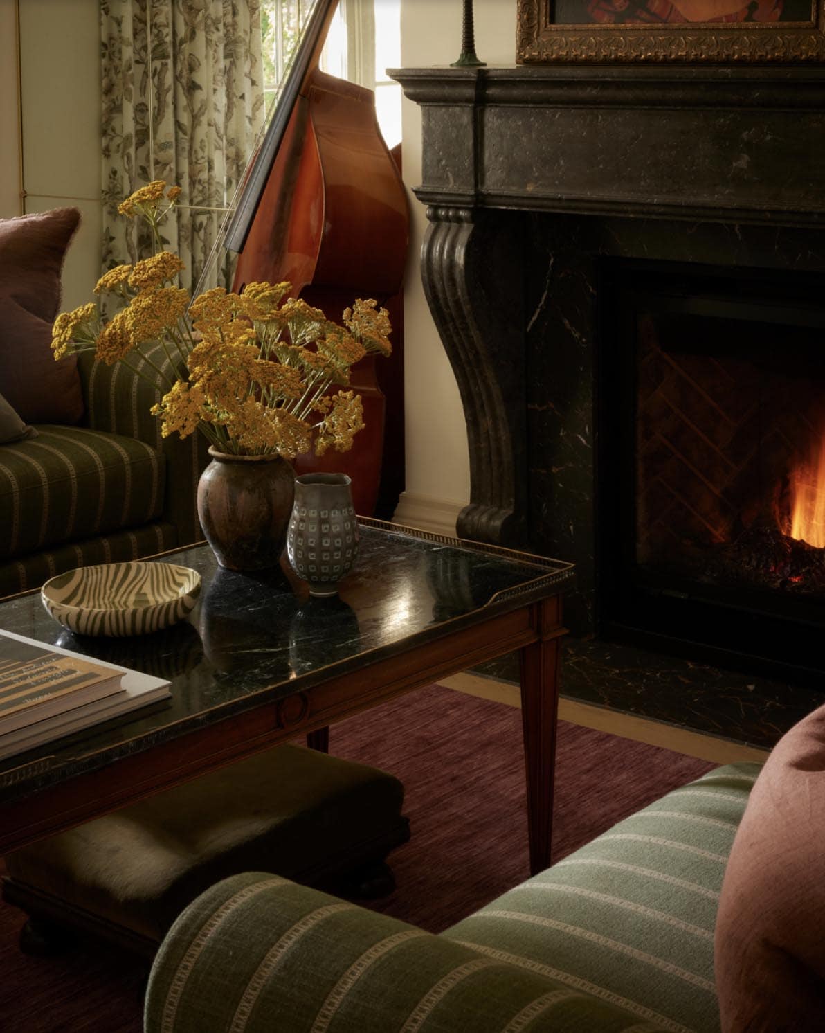 Coffee table vignette with dried flowers beside lit fireplace