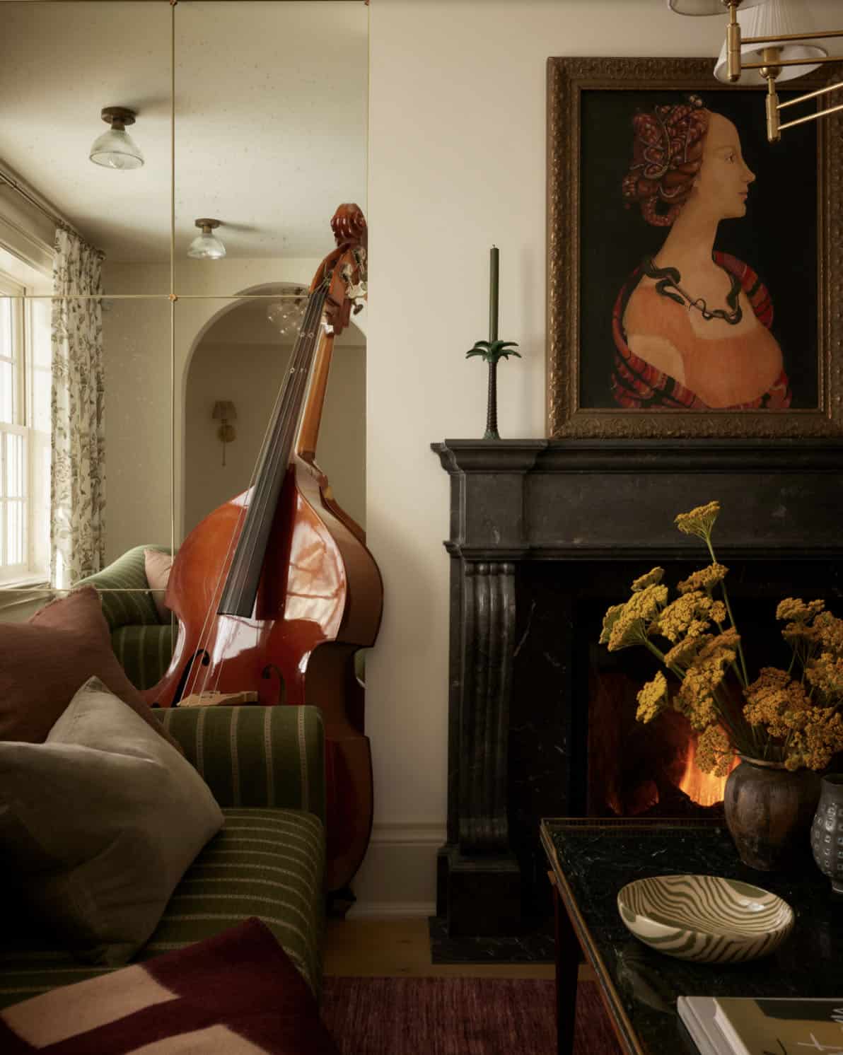 Upright bass beside black marble fireplace with portrait above