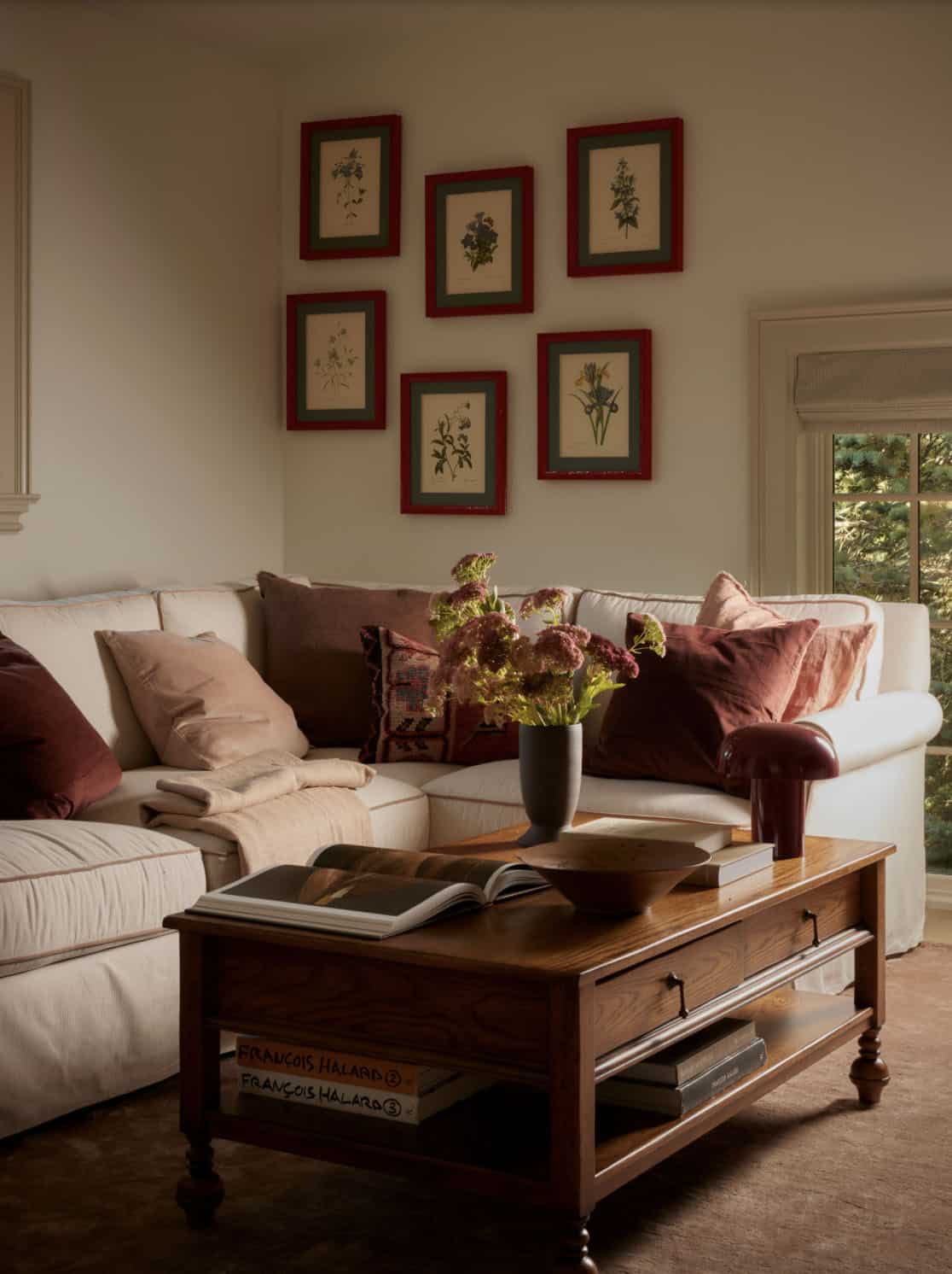 Living room sofa with botanical gallery wall and burgundy pillows