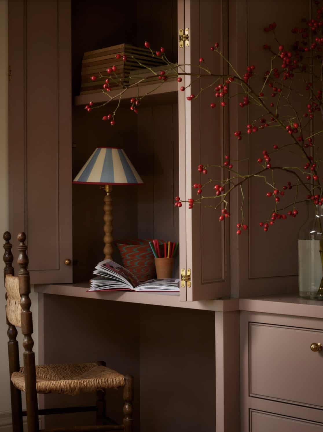 Close-up of mauve cabinet interior with striped lamp and berries
