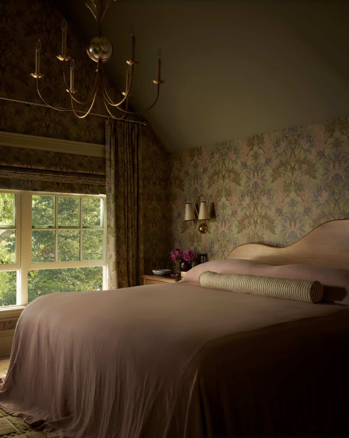 Bedroom with floral wallpaper, brass chandelier, and mauve bedding