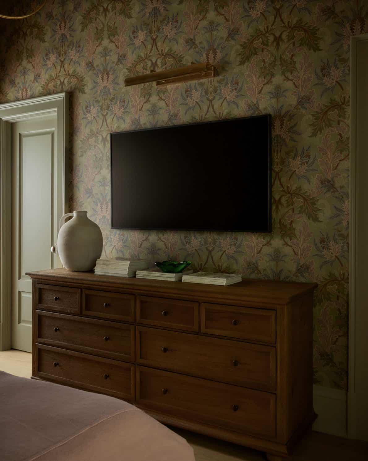 Bedroom dresser with mounted TV against floral wallpaper