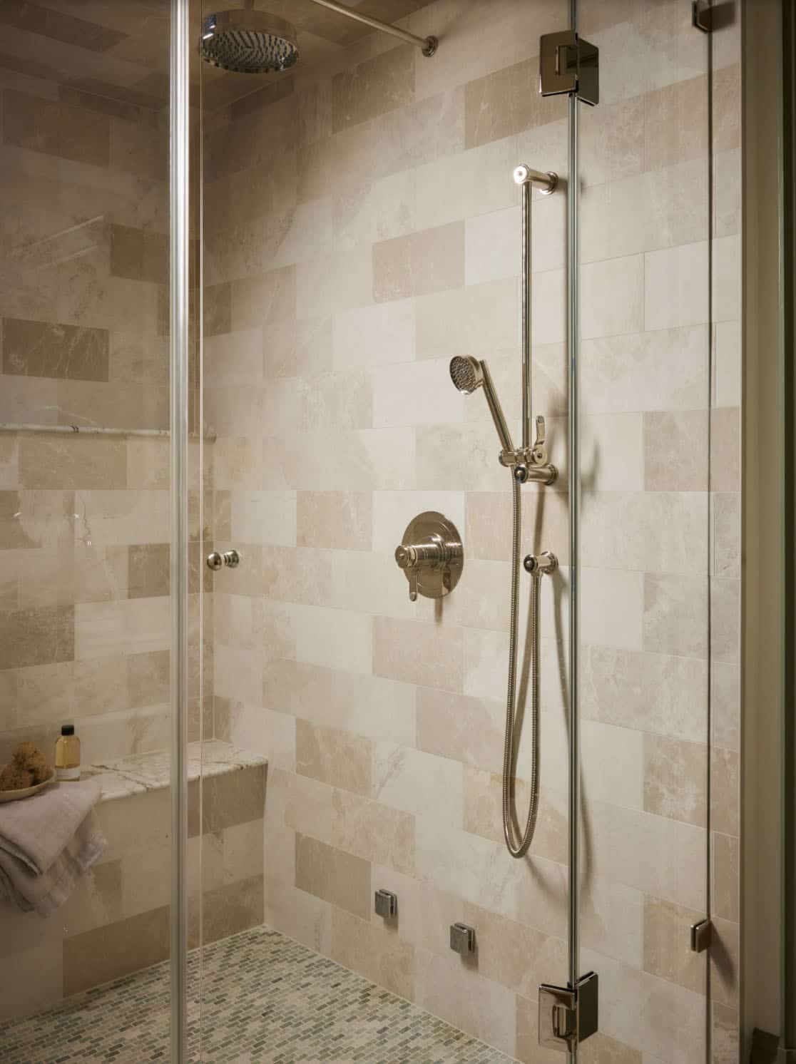 Glass-enclosed shower with tile walls and handheld sprayer