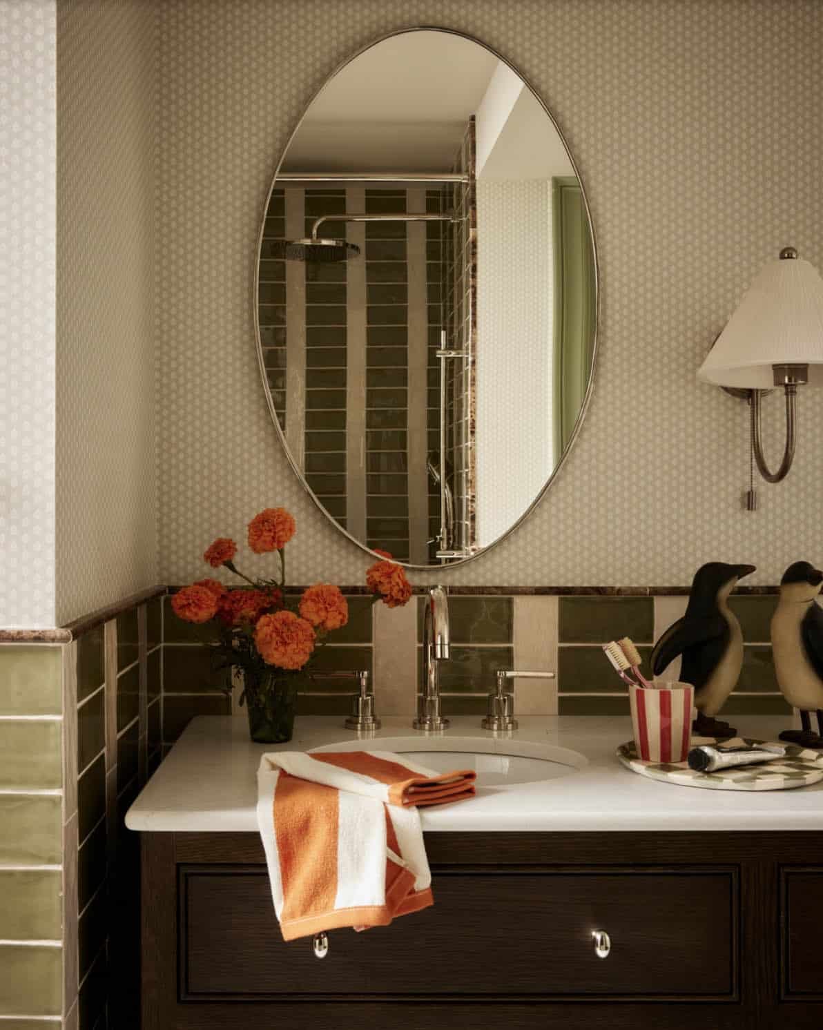 Close-up of bathroom sink with penguin figurines and marigolds