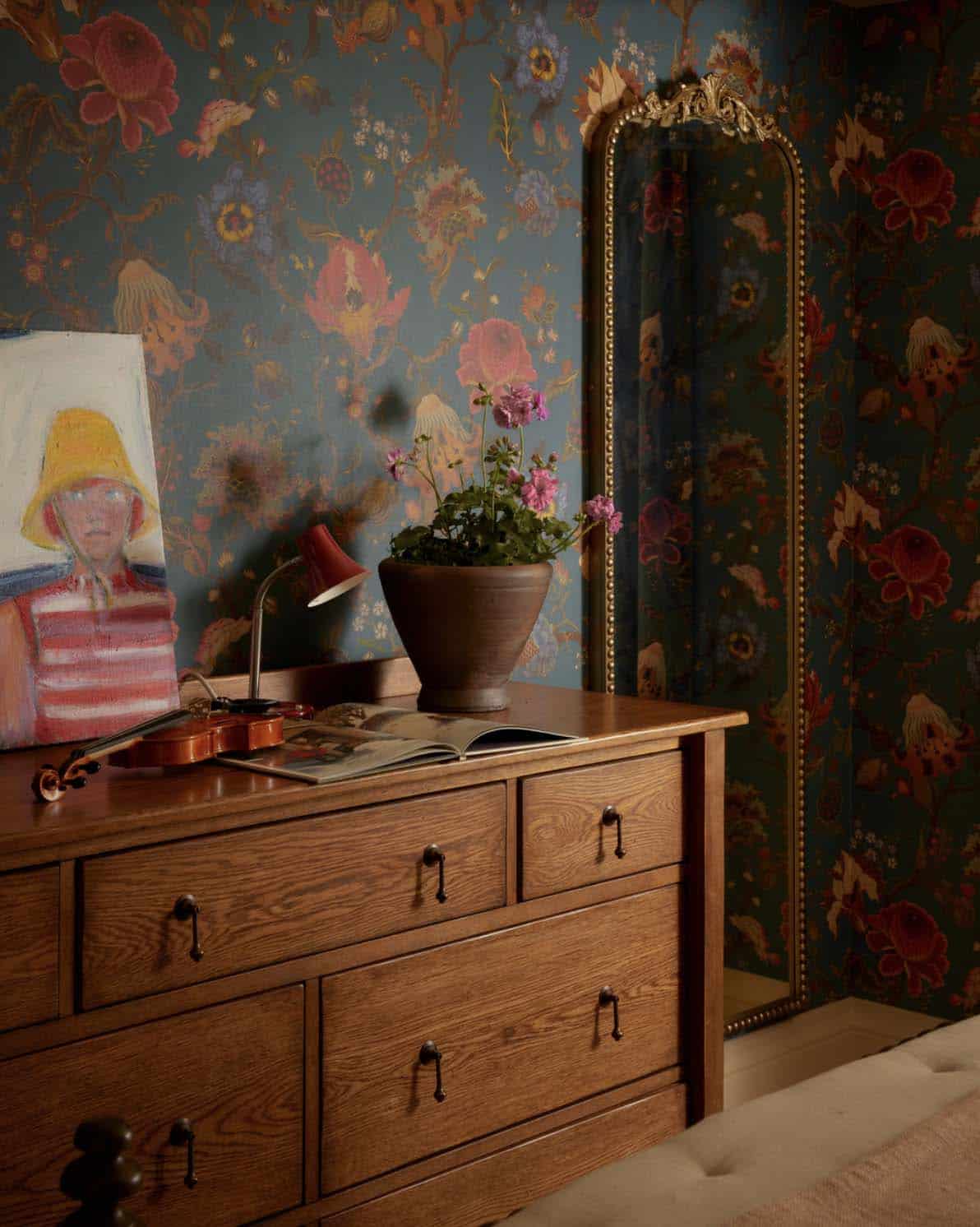 Dresser with violin and mirror against floral wallpaper
