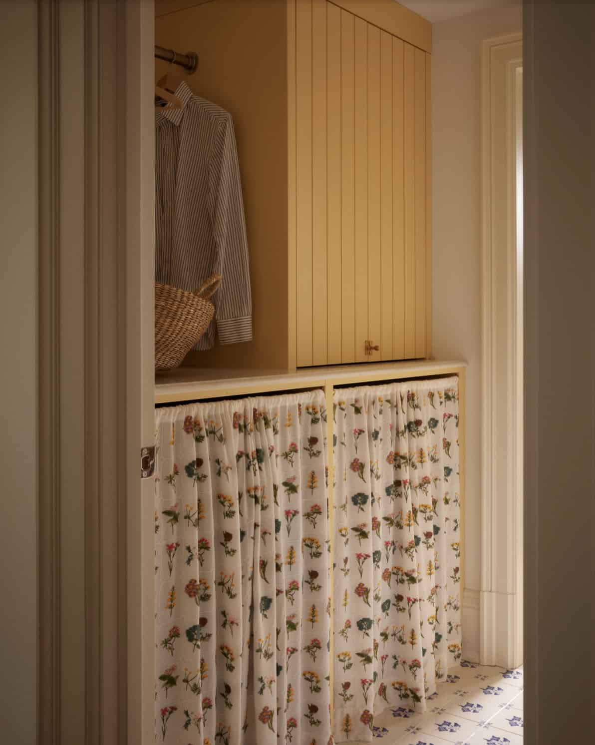 Mudroom nook with yellow cabinetry and floral curtain