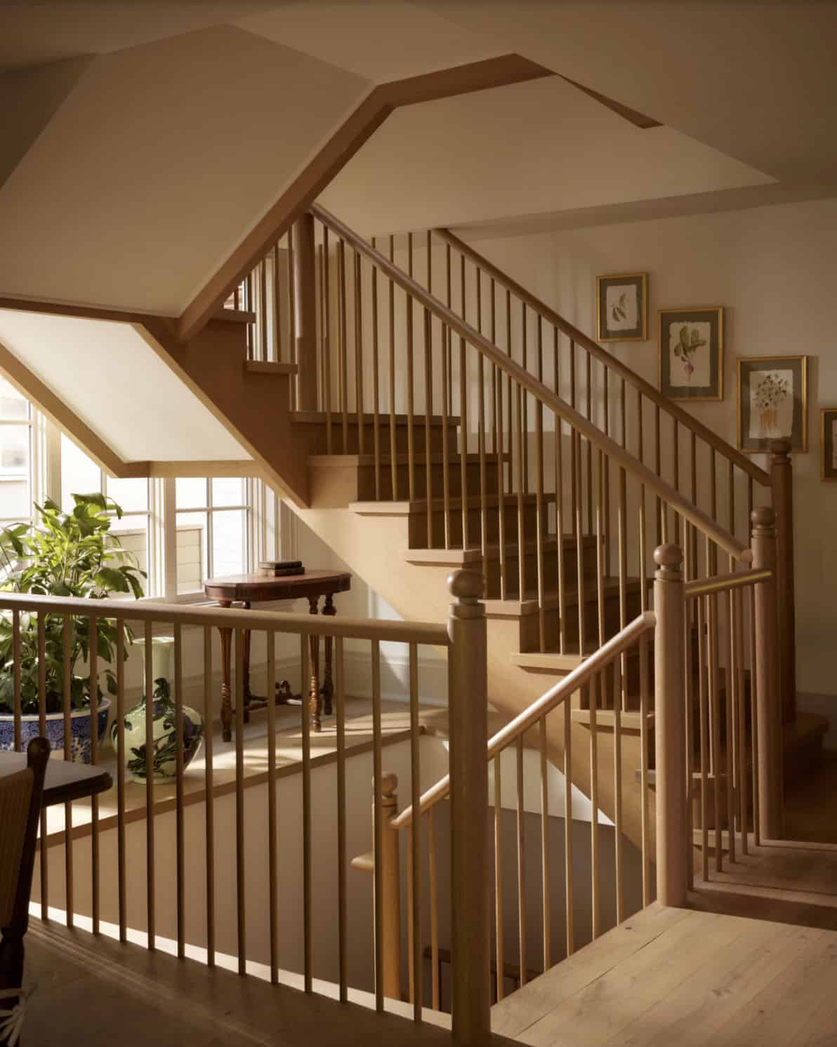 Light wood staircase with spindle railing and botanical prints