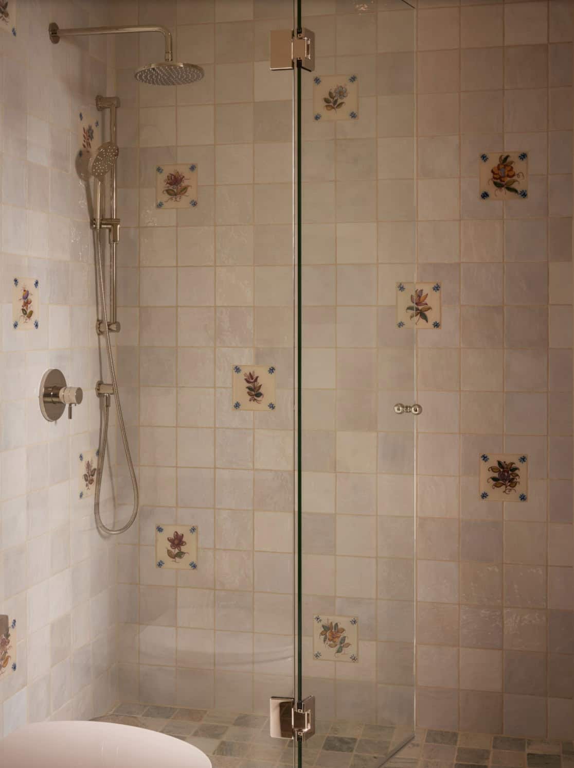 Shower stall with floral accent tiles and glass door