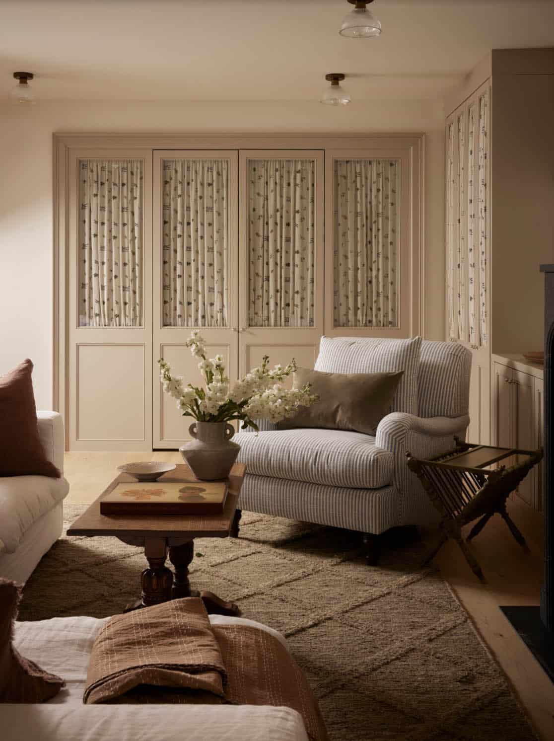 Sitting area with striped armchair and curtained cabinet doors