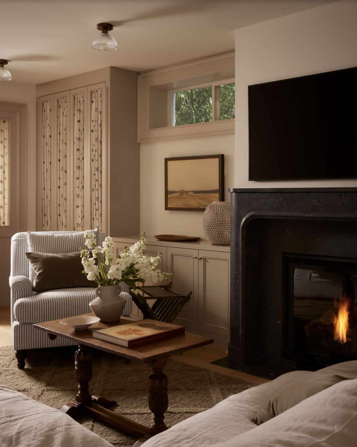 Media nook with black marble fireplace and striped armchair