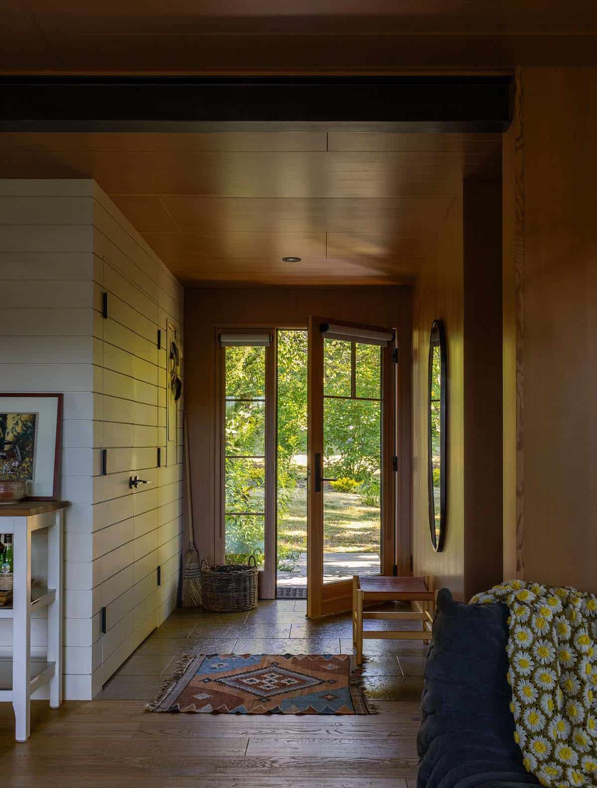 Guest cottage entry foyer with terracotta walls, shiplap accent wall, French doors, and a round mirror