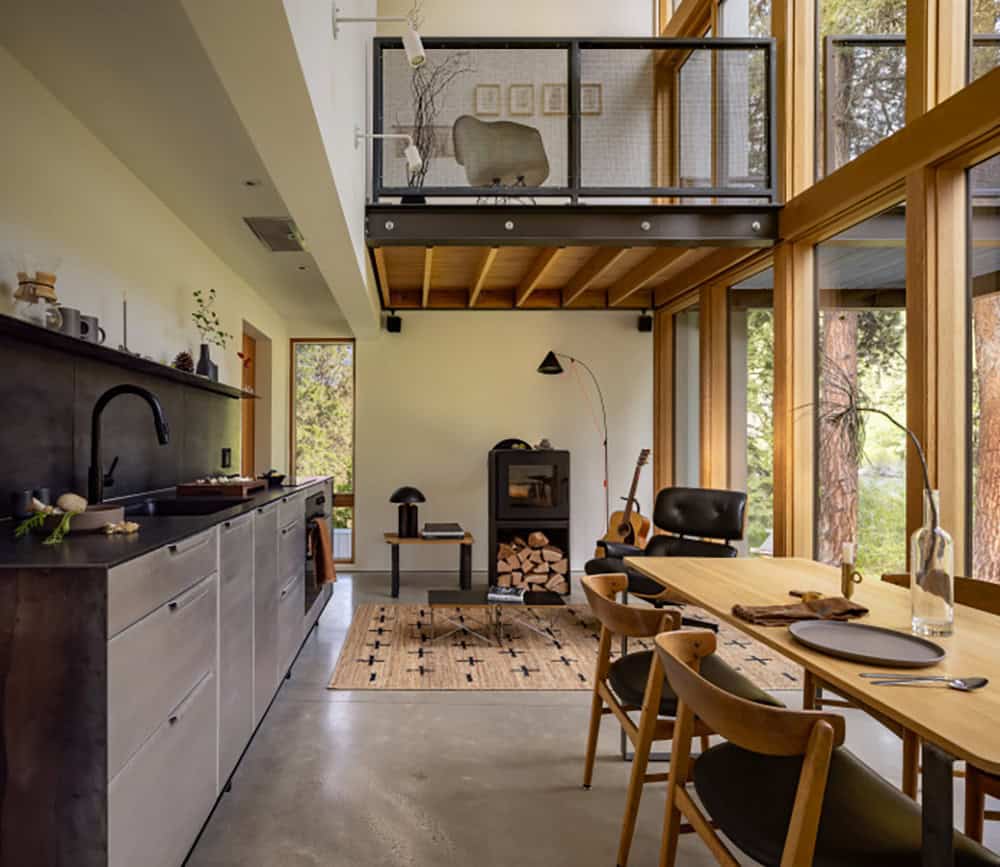 Open-plan kitchen and living room with mezzanine loft and floor-to-ceiling forest views
