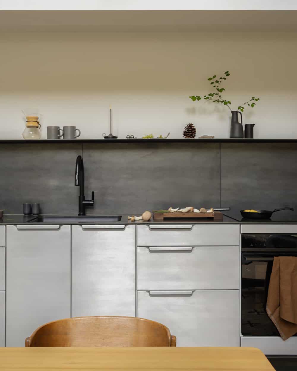 Modern kitchen detail with stainless steel cabinets and dark concrete backsplash