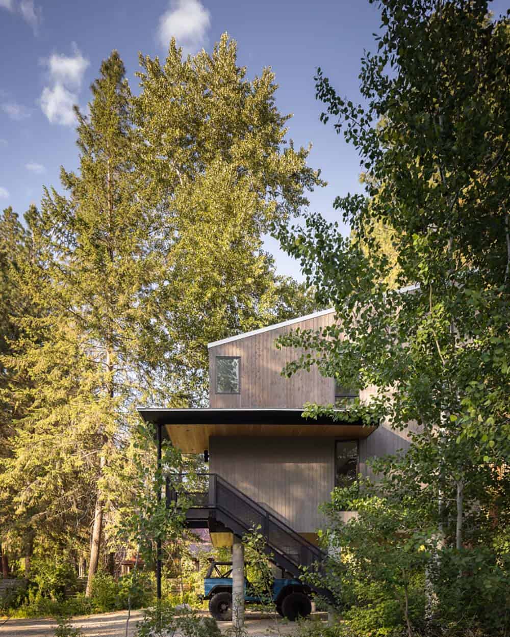 Wood-clad cabin elevated on concrete piers surrounded by aspen and pine trees