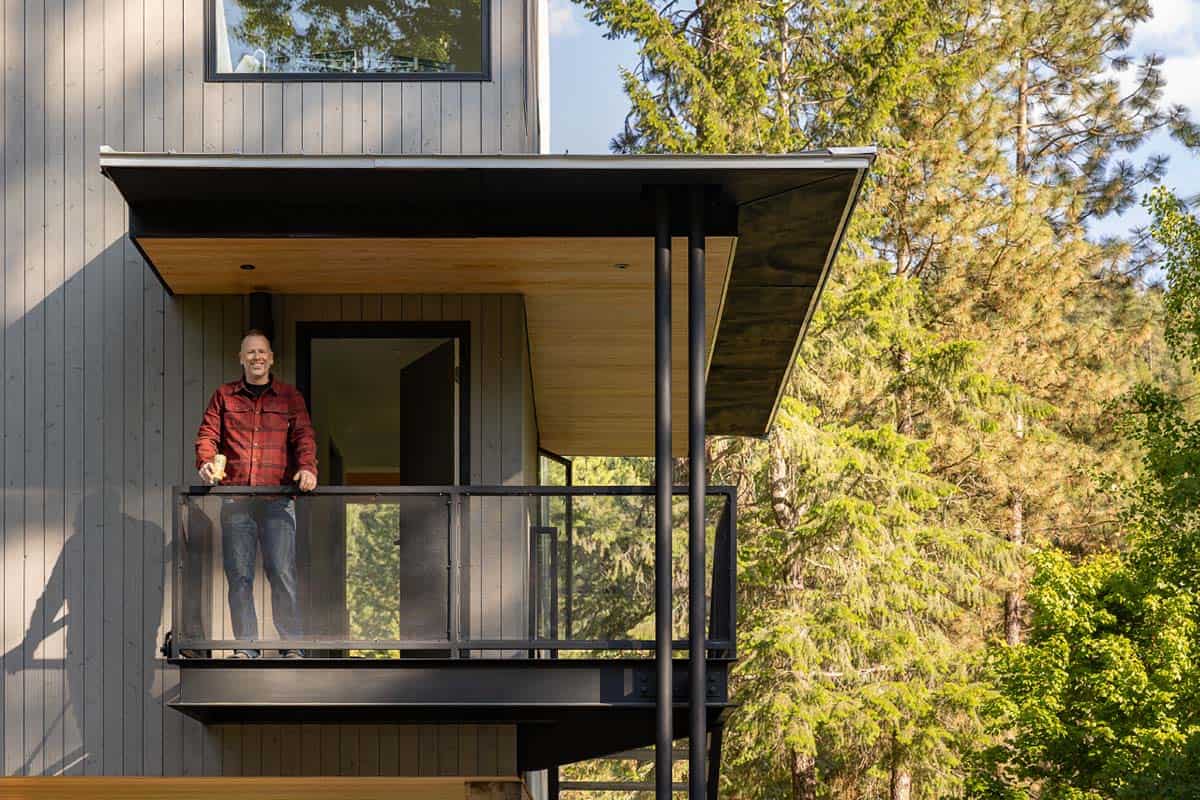 Man standing on elevated entry deck of modern forest cabin Washington