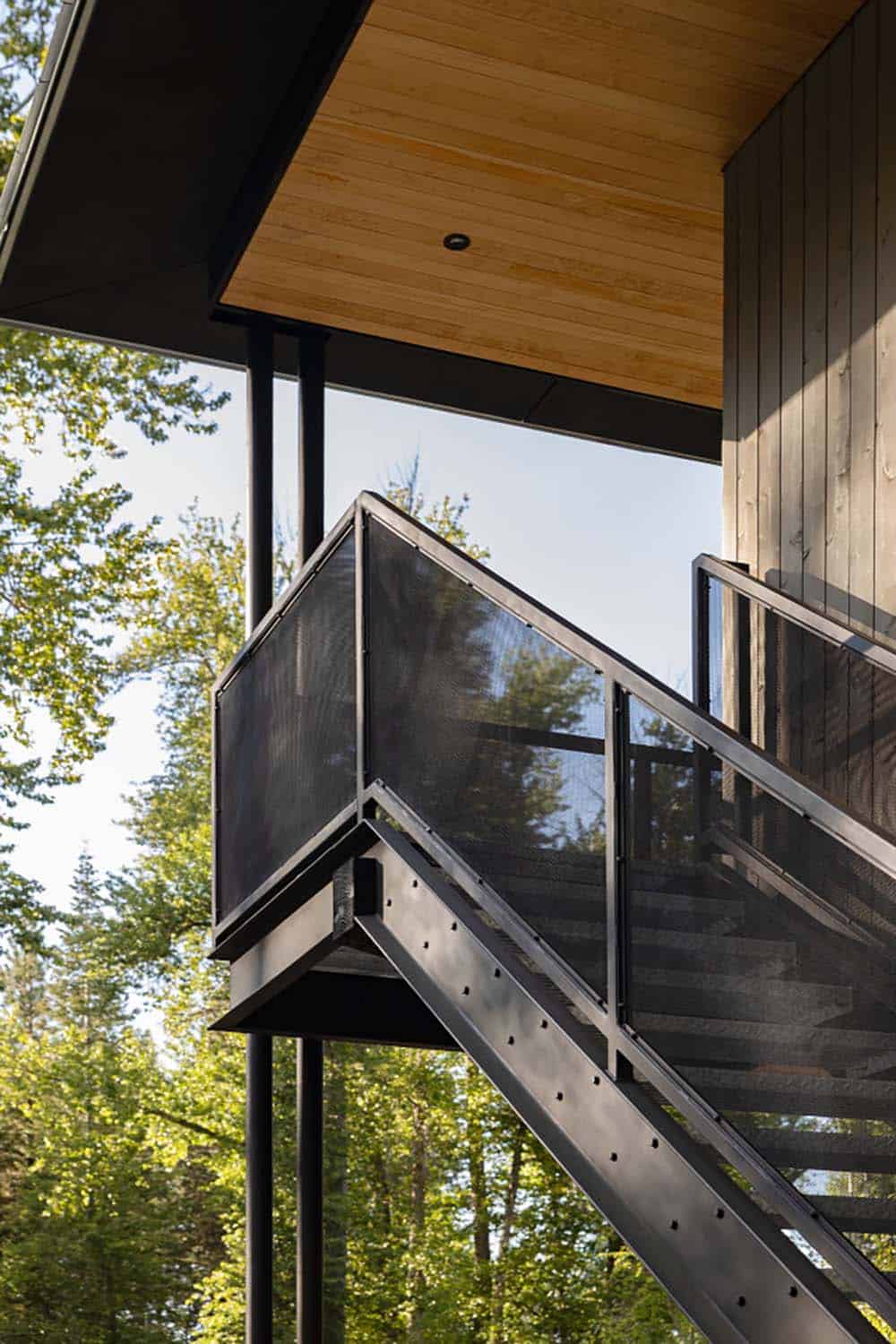 Black steel staircase and perforated metal balcony detail on elevated cabin