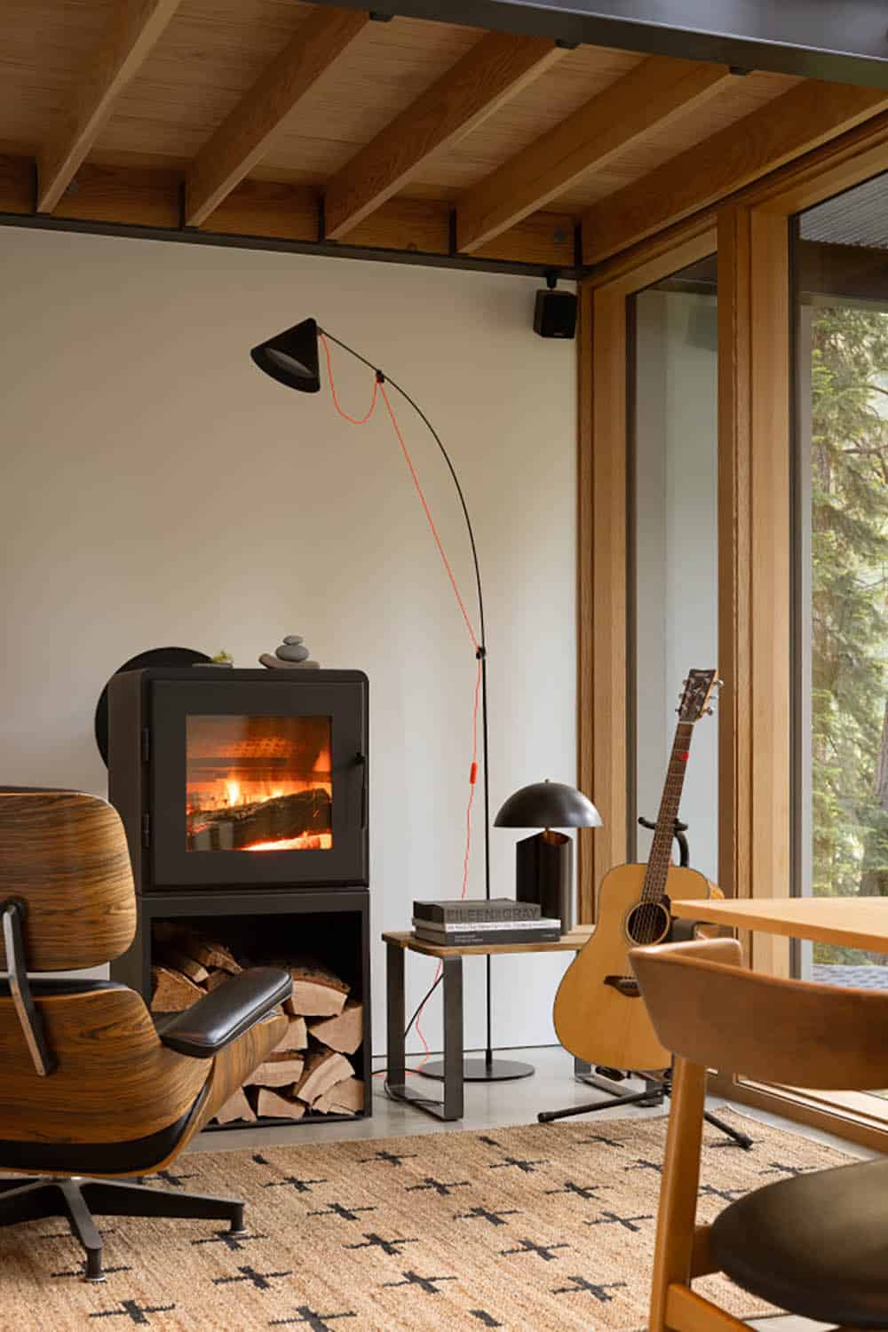 Living room with wood-burning stove Eames lounge chair and acoustic guitar