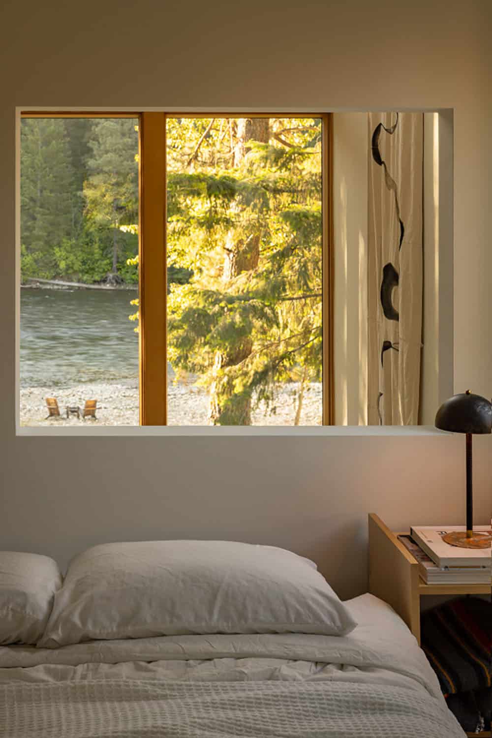 Bedroom with framed window view of Wenatchee River and sunlit pine trees