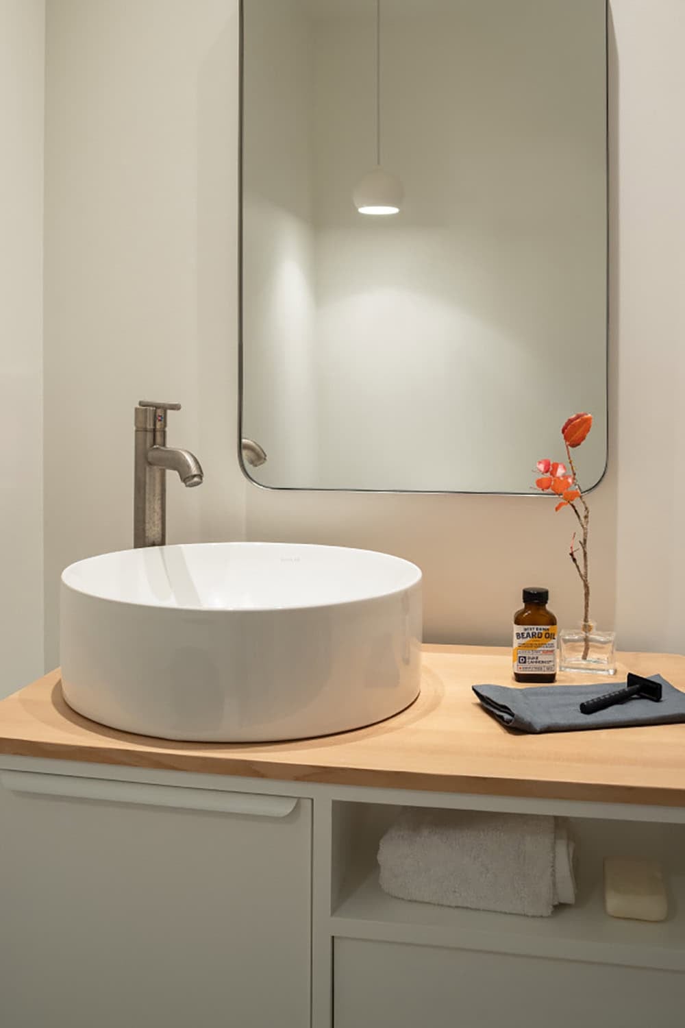 Round vessel sink on wood vanity with round mirror and pendant light