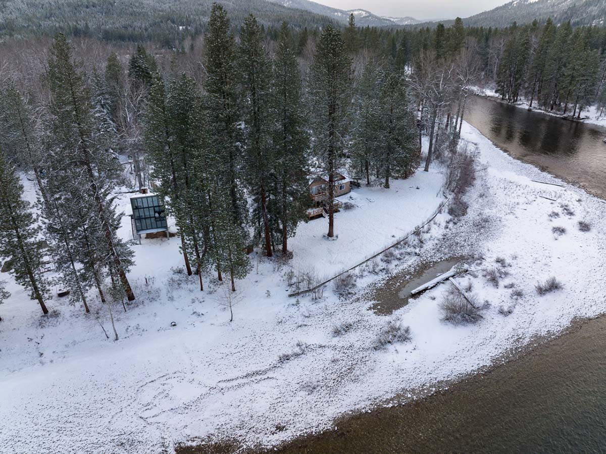 Aerial winter view of modern cabin and farmhouse on snowy Wenatchee River bank
