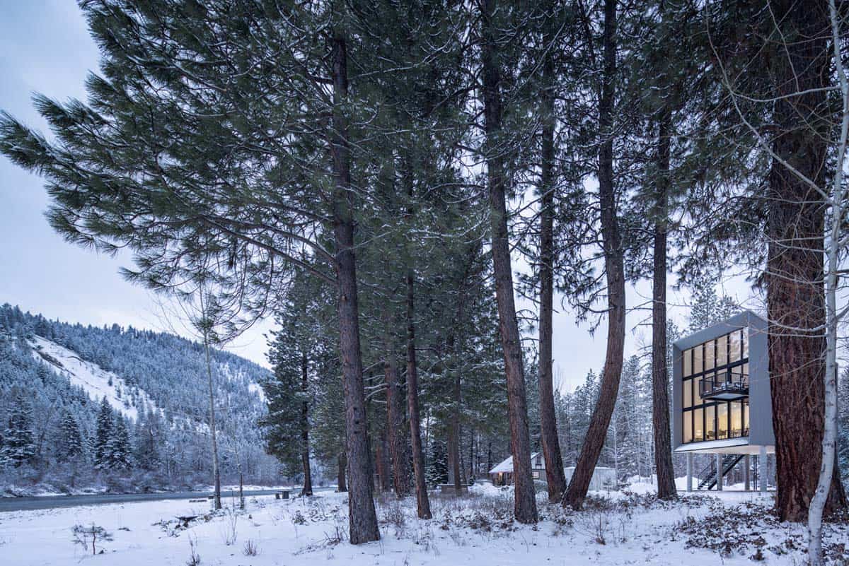 Glowing modern cabin beside Wenatchee River in blue winter dusk light