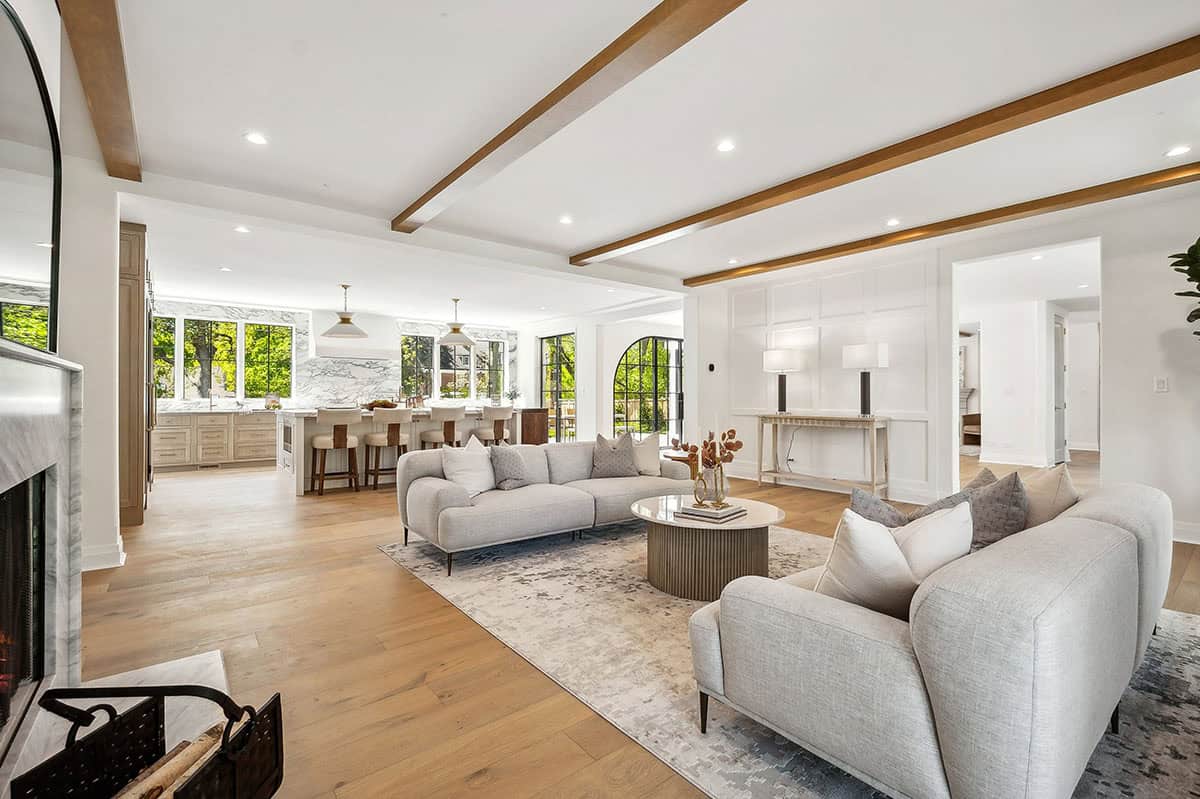 Living room with beamed ceiling opening to kitchen beyond