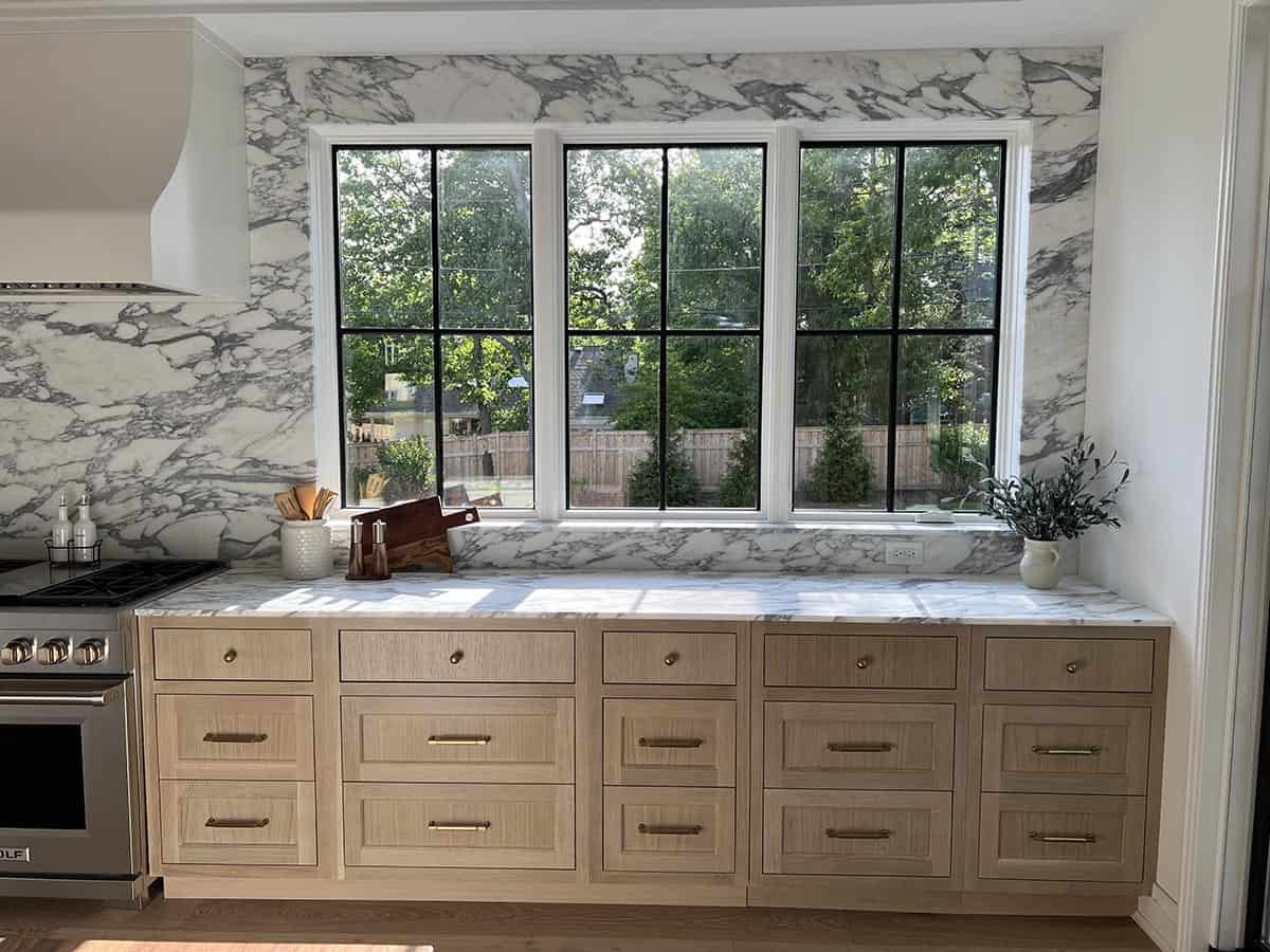 Kitchen breakfast nook with marble slab wall, steel-framed windows, and oak drawer base cabinets