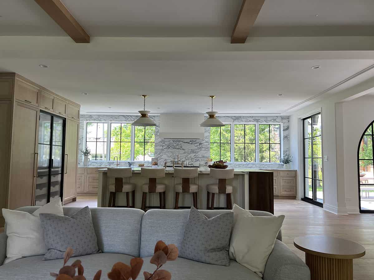Wide shot of great room with exposed wood beams, kitchen island, and glass door to patio