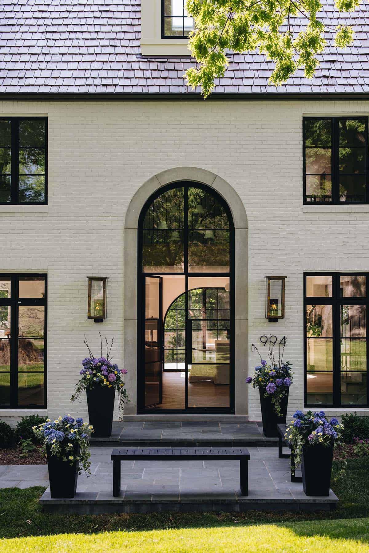Front door detail with arched stone entryway open to reveal herringbone floors and living room beyond