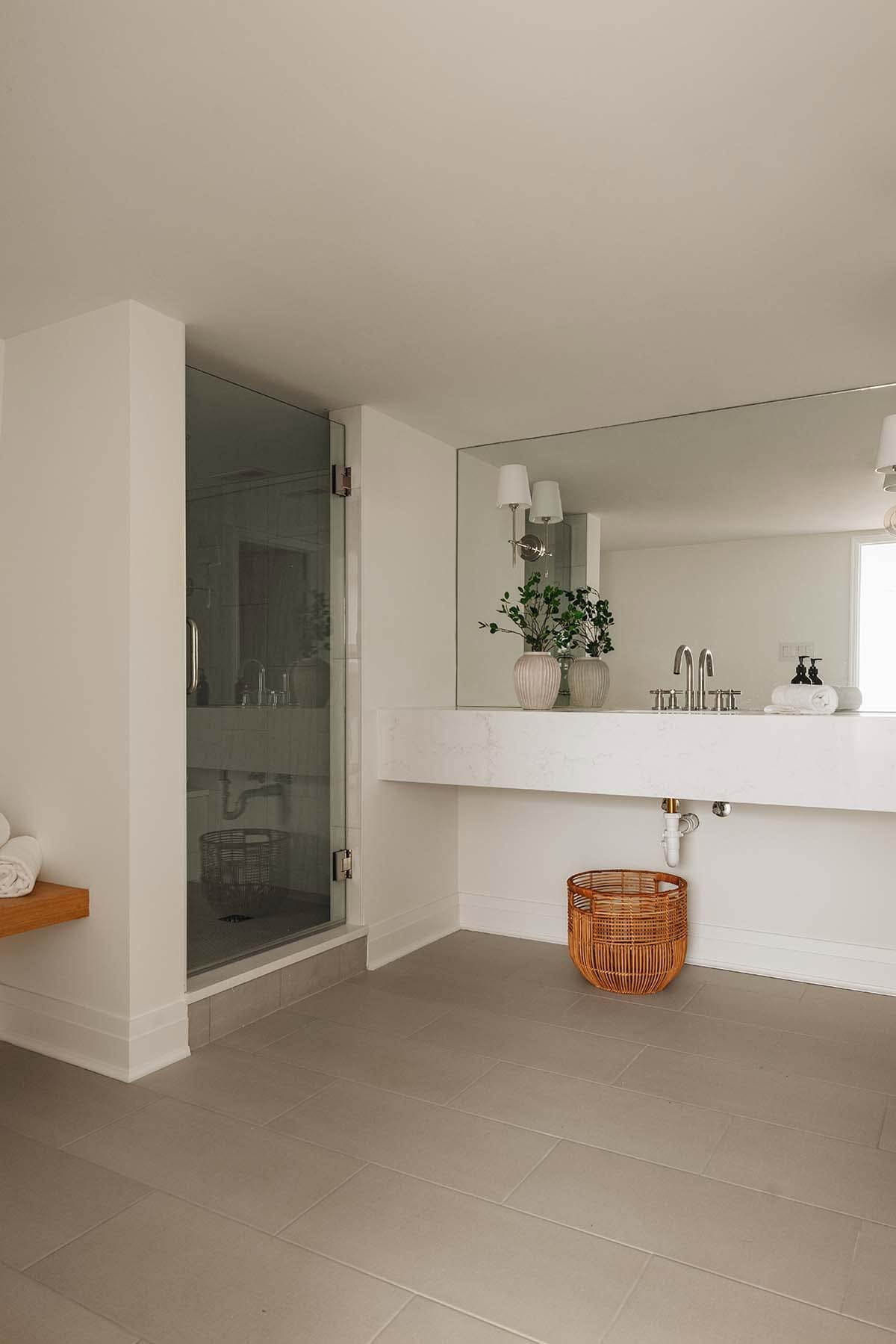 Spa bathroom with glass-enclosed shower, floating marble vanity, and woven rattan basket