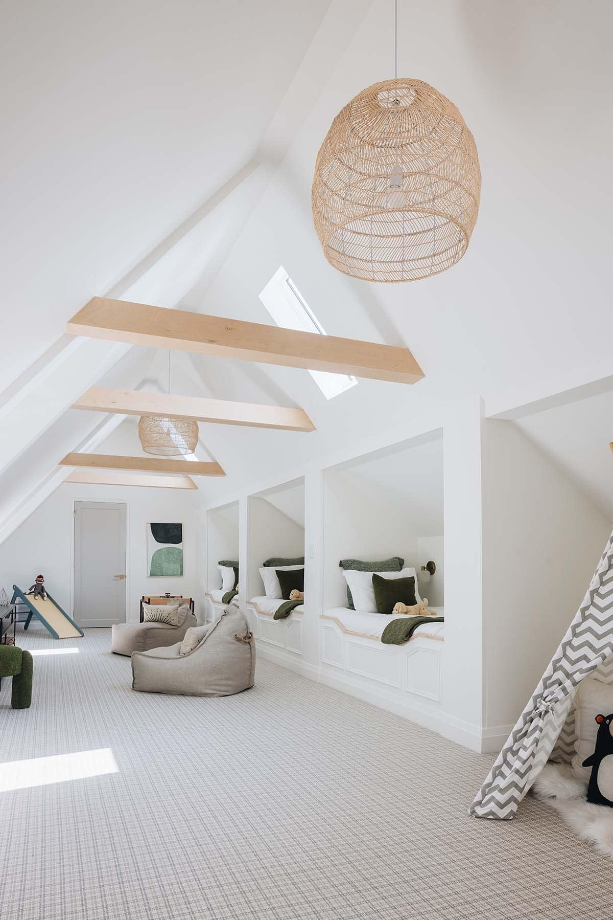 Wide view of children's bunk room with peaked ceiling, skylights, teepee tent, and bean bags