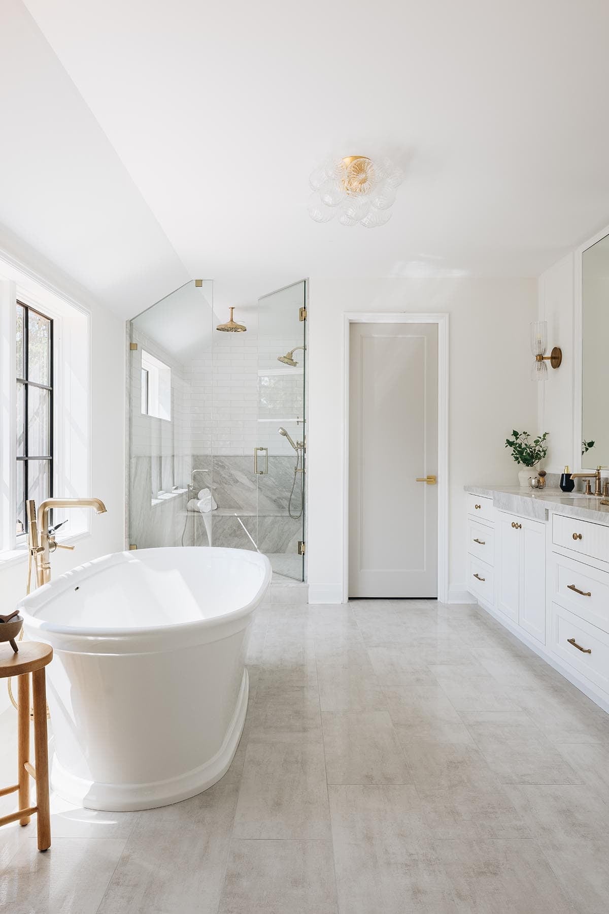 Primary bathroom with freestanding oval soaking tub, brass floor-mount faucet, and glass shower