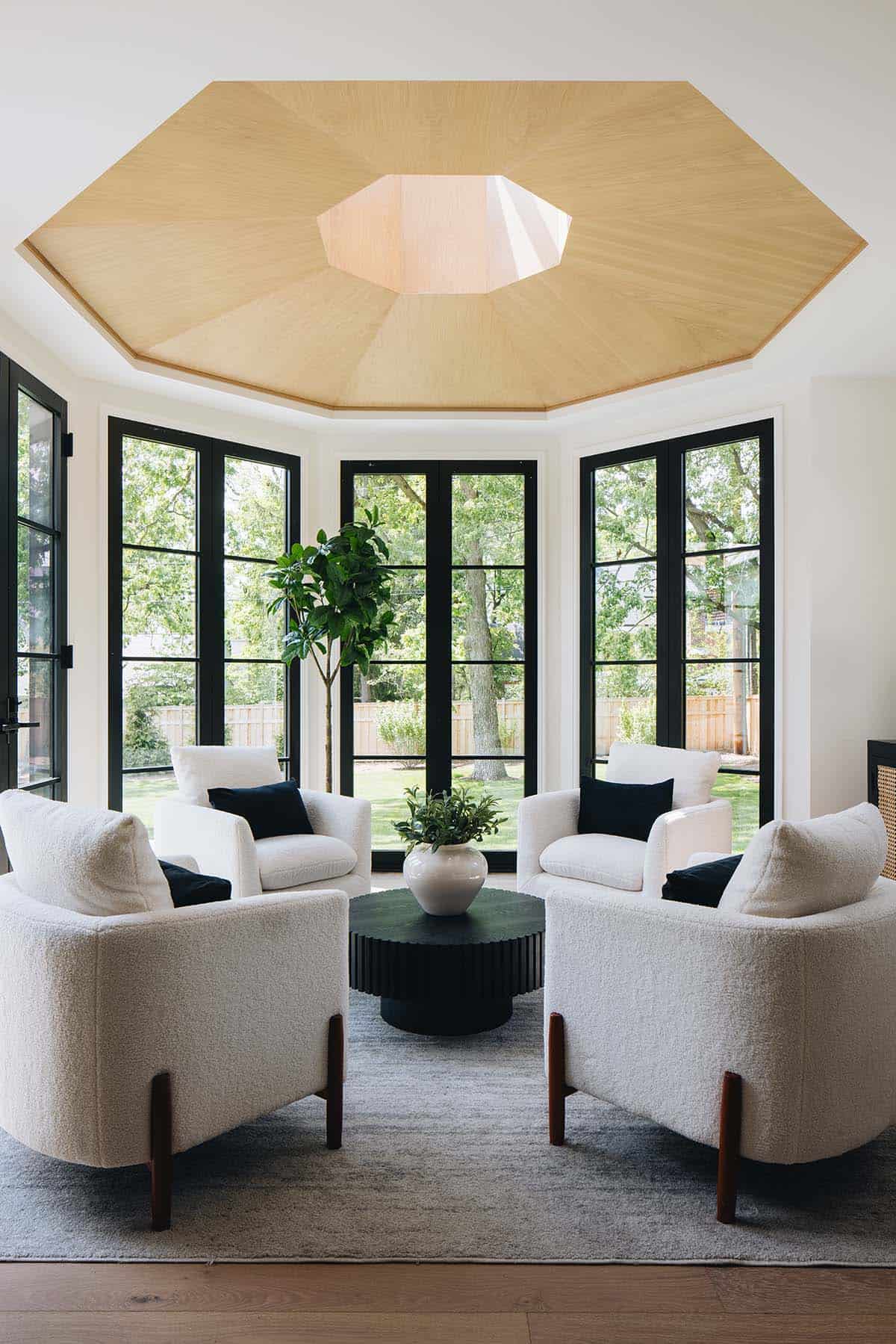 Octagonal sunroom ceiling with wood paneling, skylight, and boucle chairs around round coffee table