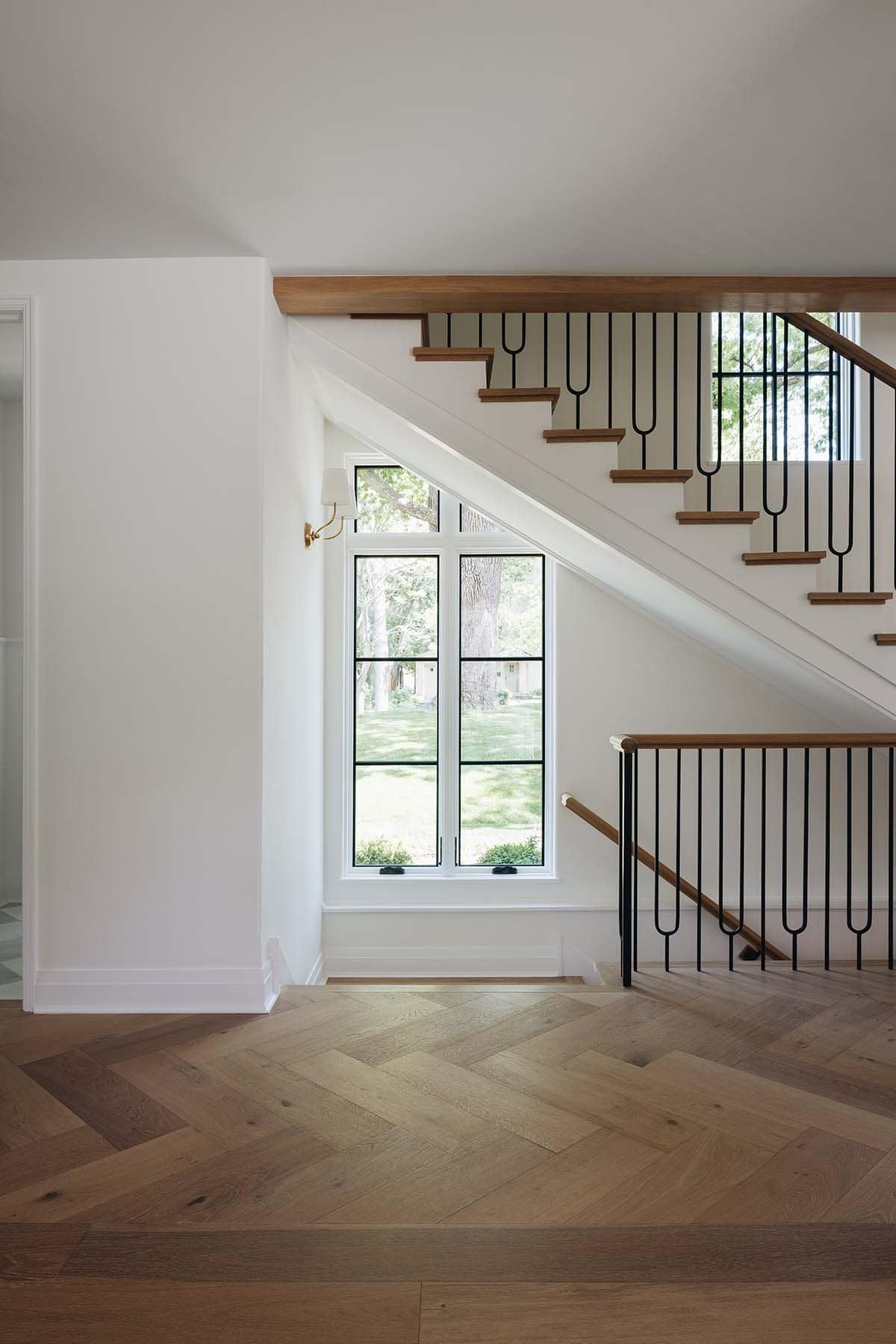 Understair nook with arched window, wood staircase, and black iron railing detail