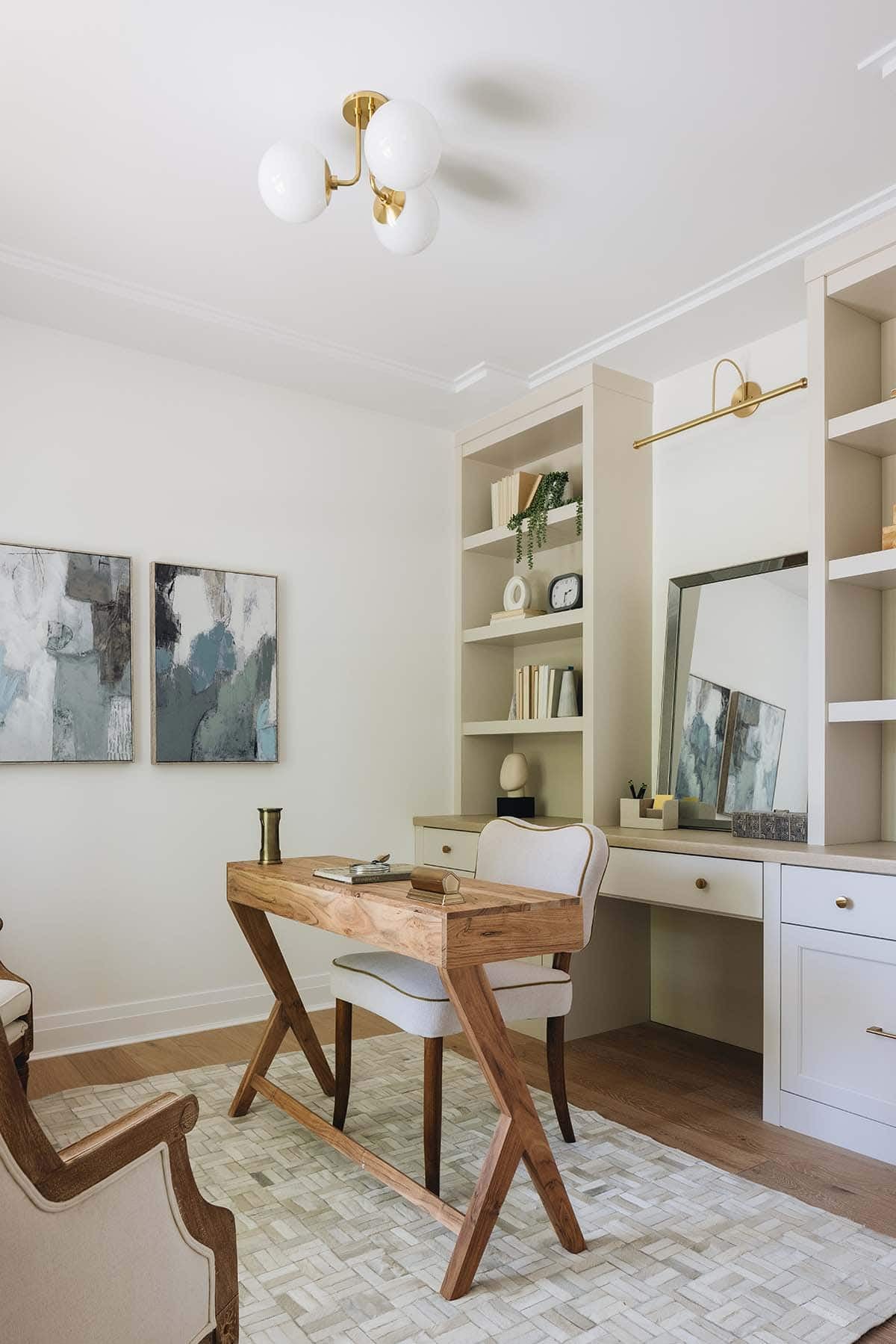 Home office vanity nook with built-in shelving, wood desk, and abstract wall art