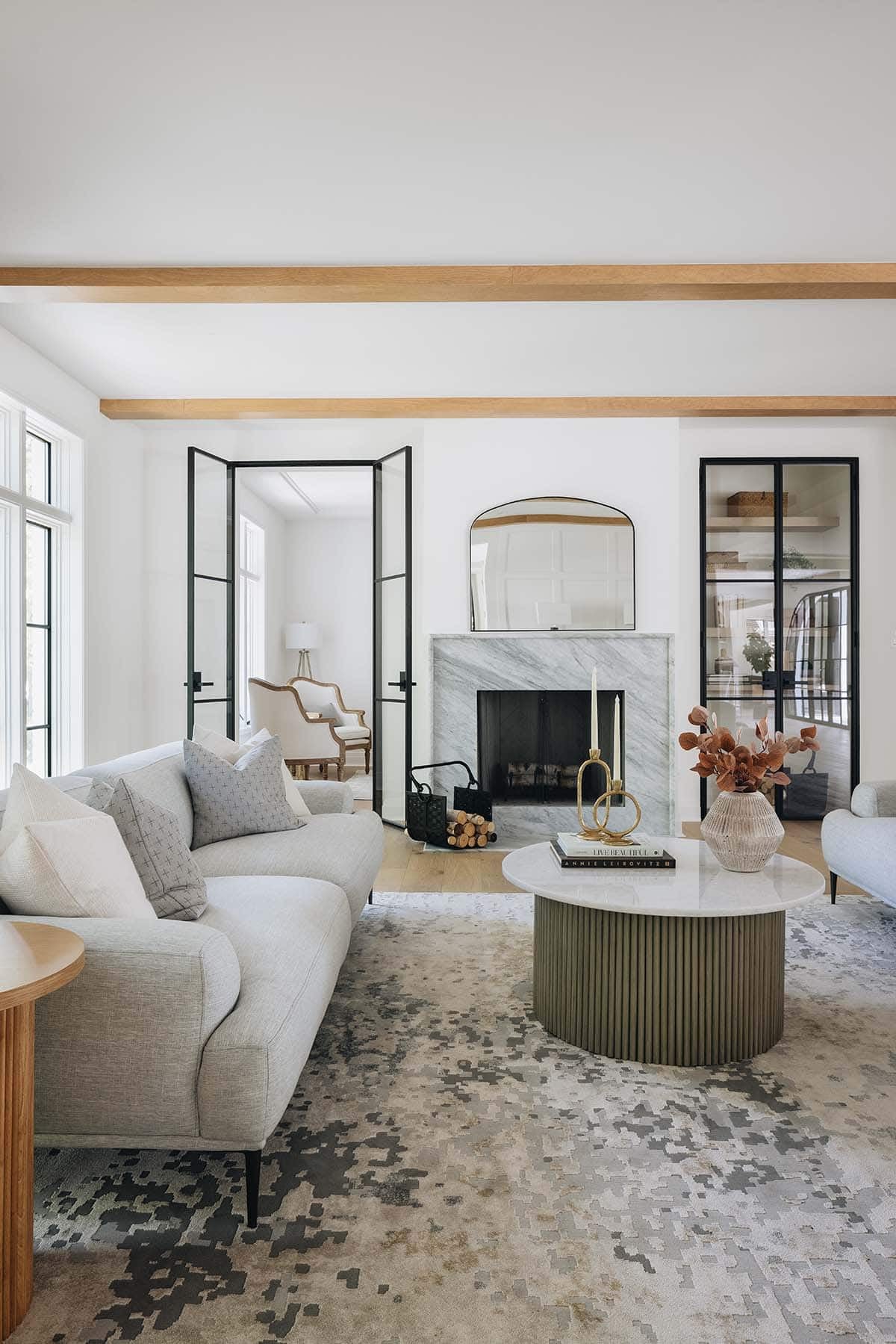 Living room with gray sofas, marble fireplace, glass-front cabinet, and ribbed coffee table