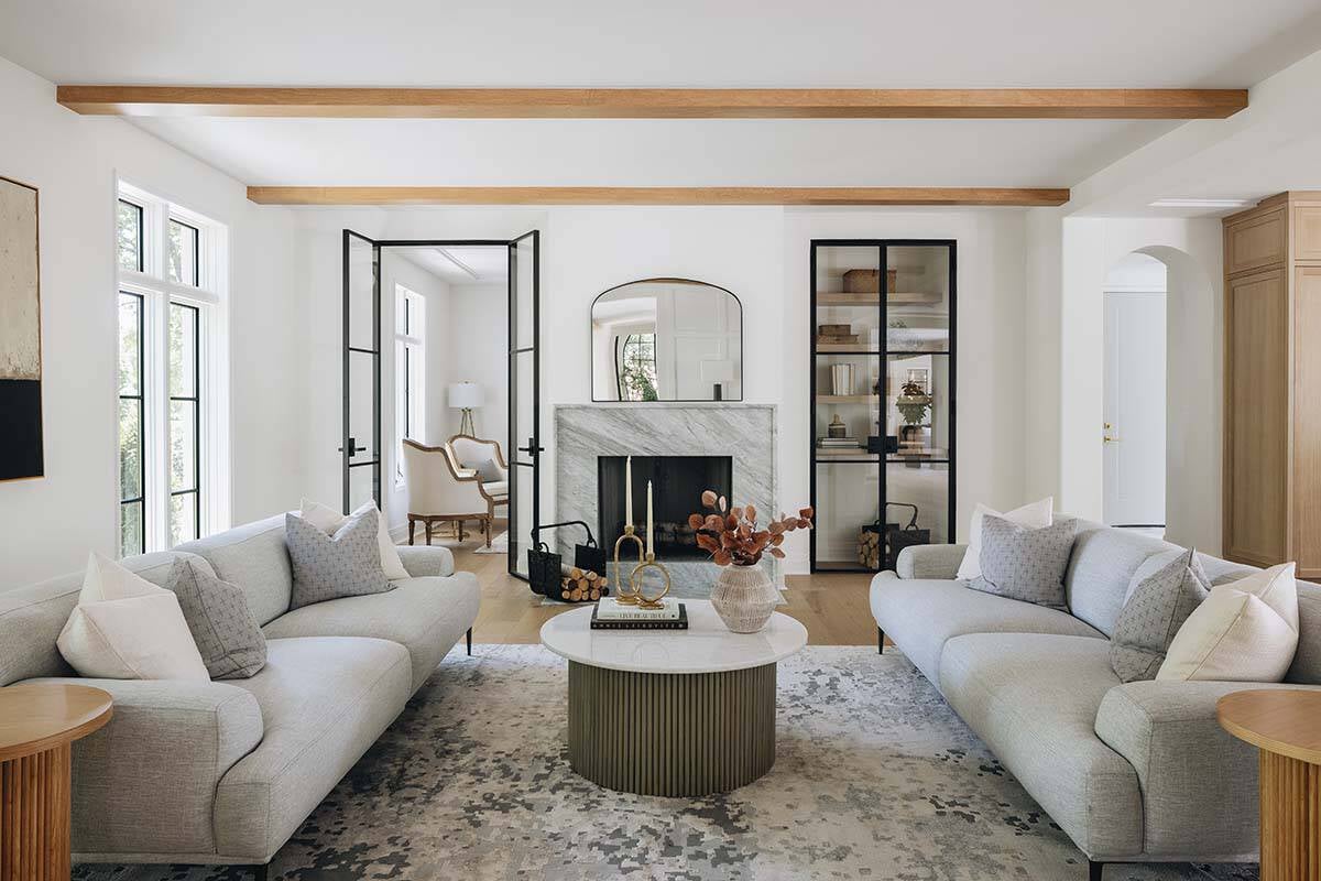 Wide living room view with dual sofas facing marble fireplace and glass French doors